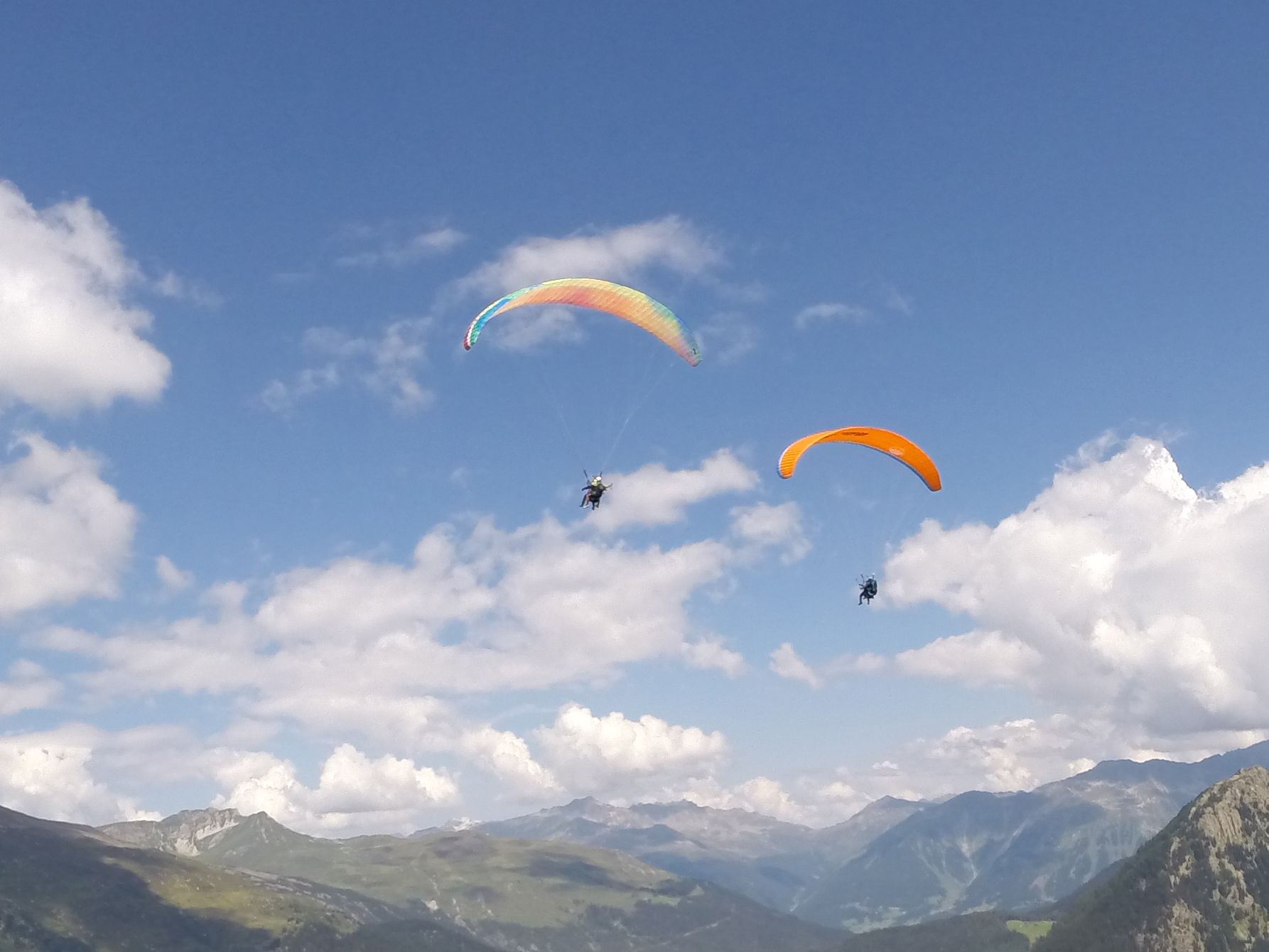 Vzdušný tandemový let s kluzáky nad Davos v létě, viditelné modré nebe a hory.