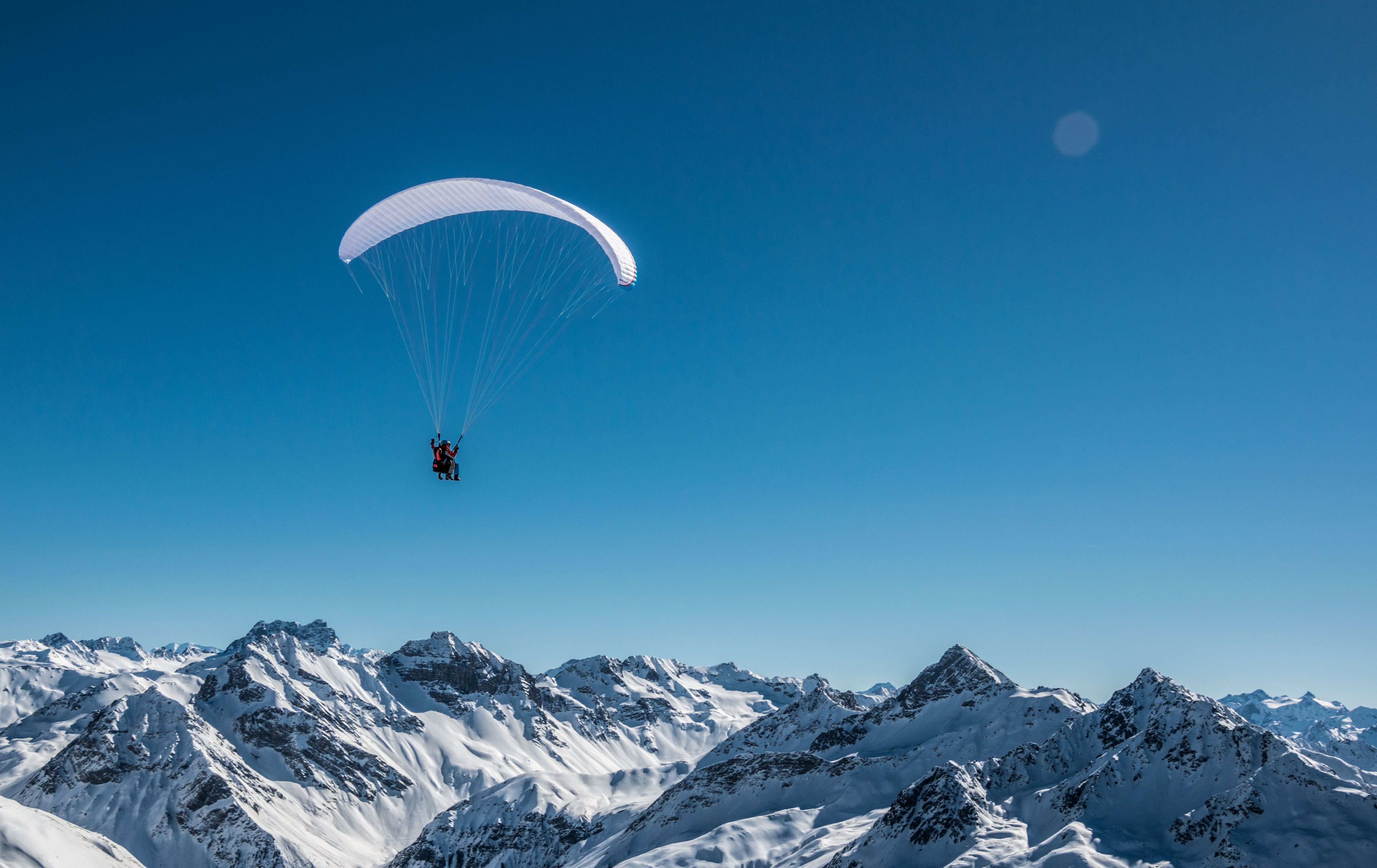 Tandemvlucht met de parachute boven sneeuwbedekte bergen in de winter.