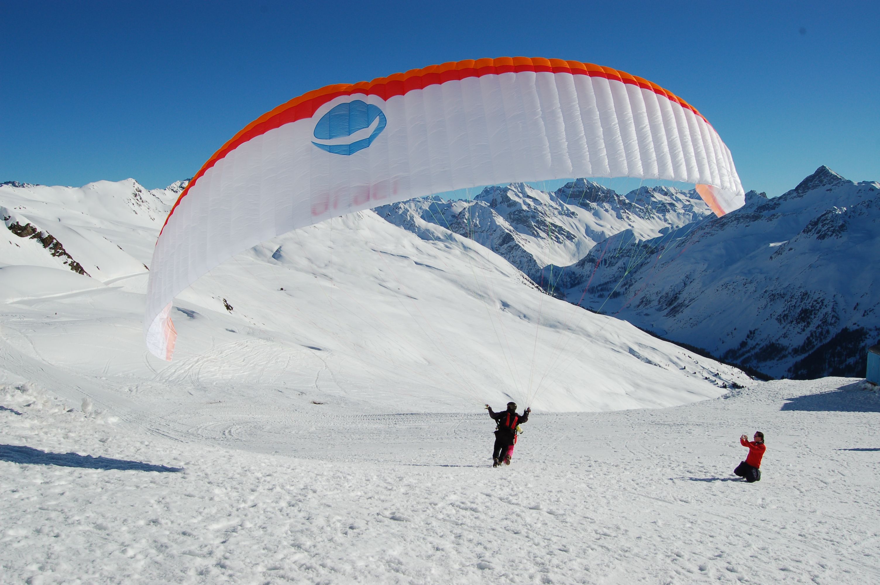 Tandemvlucht met een parapente boven besneeuwde bergen in Graubünden in de winter