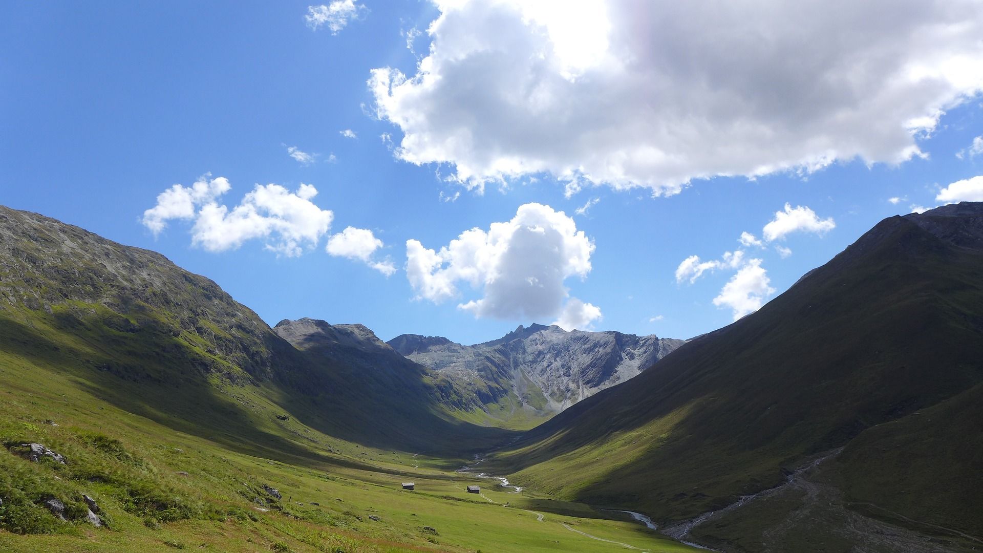 풍경: 인상적인 산악 풍경과 녹색 초원, 배경에는 푸른 하늘이 있습니다.
