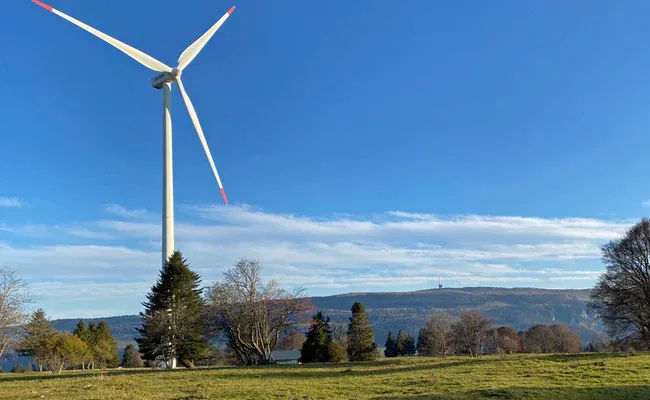 Kincir angin di Jura Seeland dengan langit biru, latar belakang bukit-bukau.