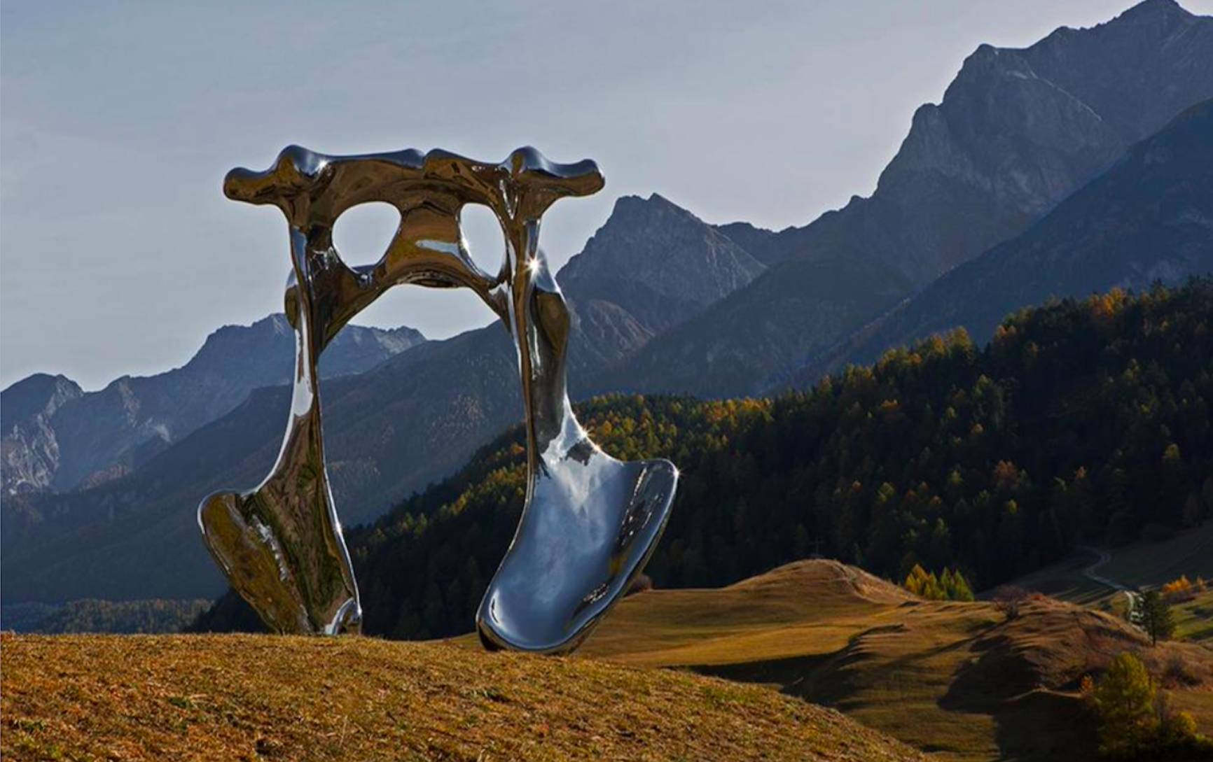 Kamelová nádrž: Kovová socha v horách obklopená pestrou přírodou.