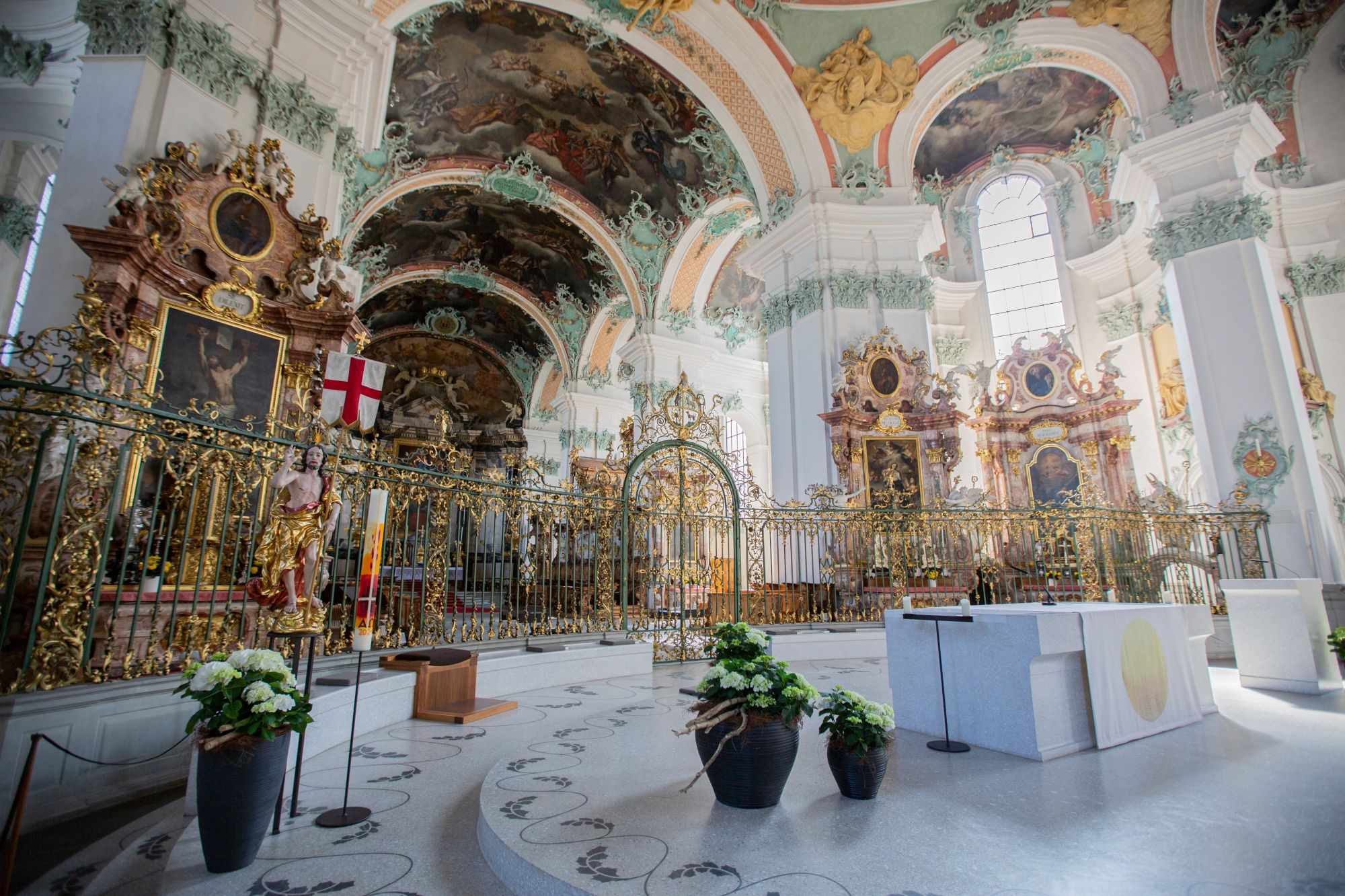 Interior of the cathedral with ornate frescoes, opulent altars, and floral arrangements.