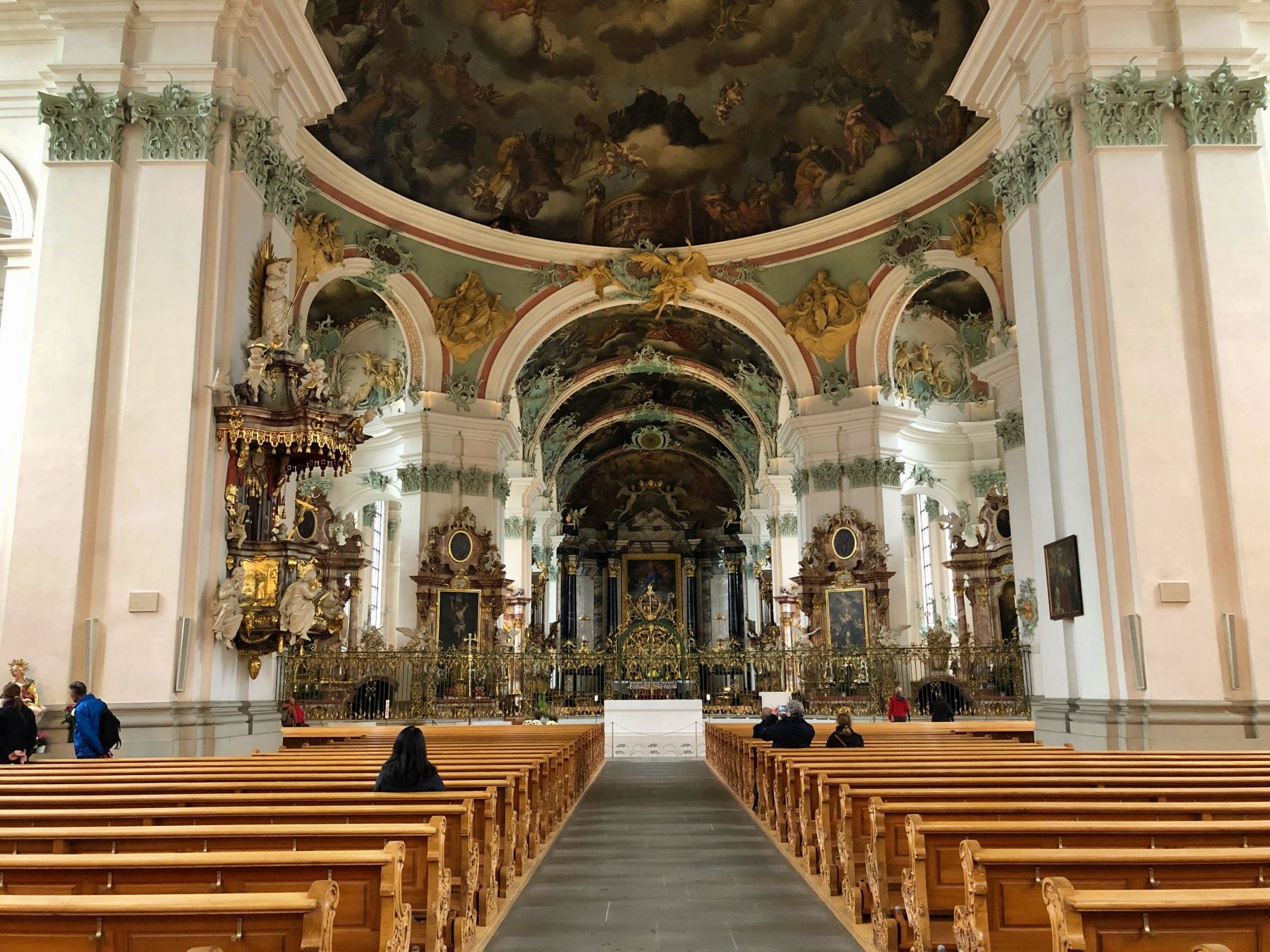 Interior of the cathedral with benches, decorative ceiling, and altars.