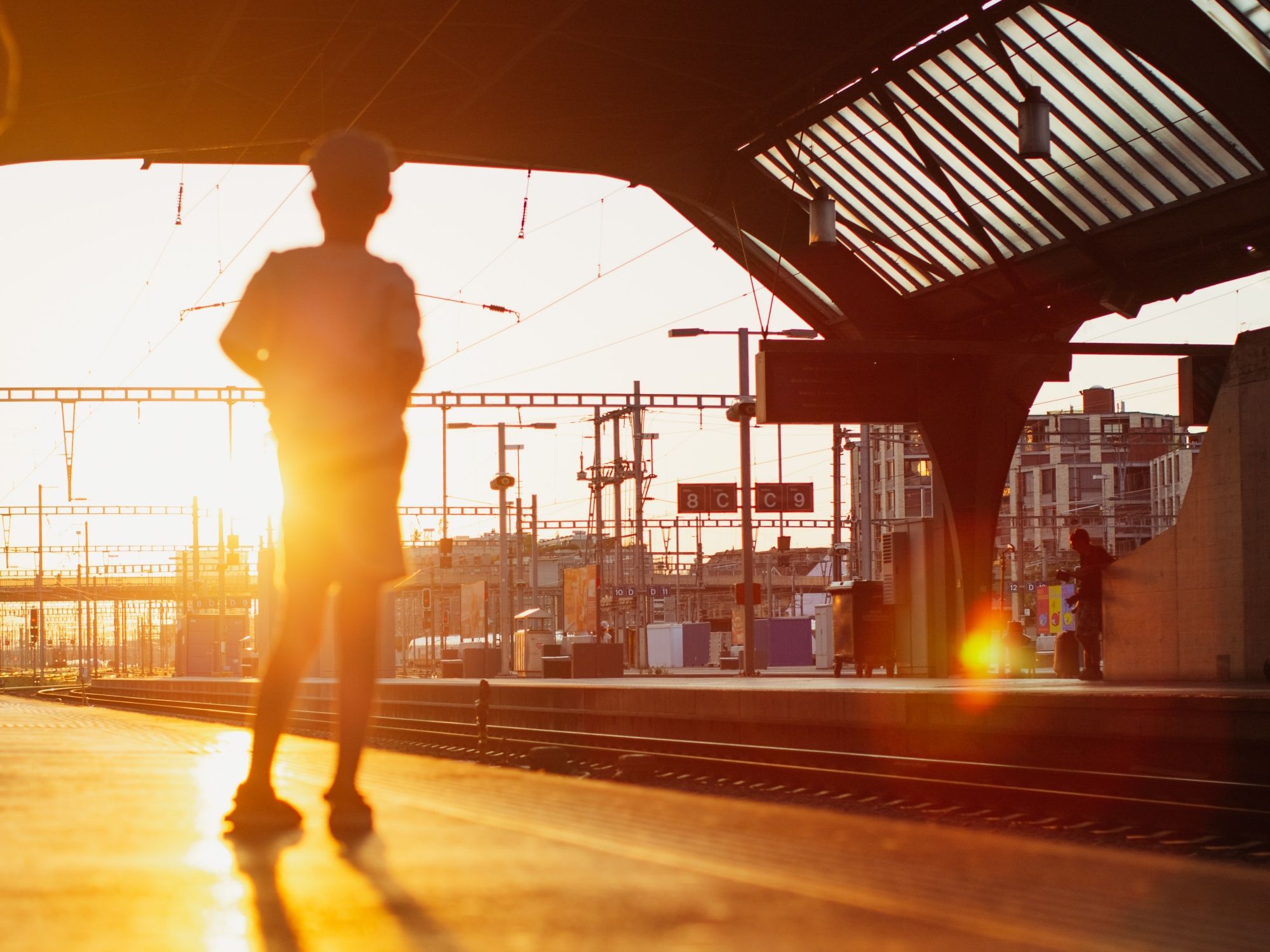 역: 아이가 석양 속 기차역의 승강장에서 실루엣으로 서 있다.