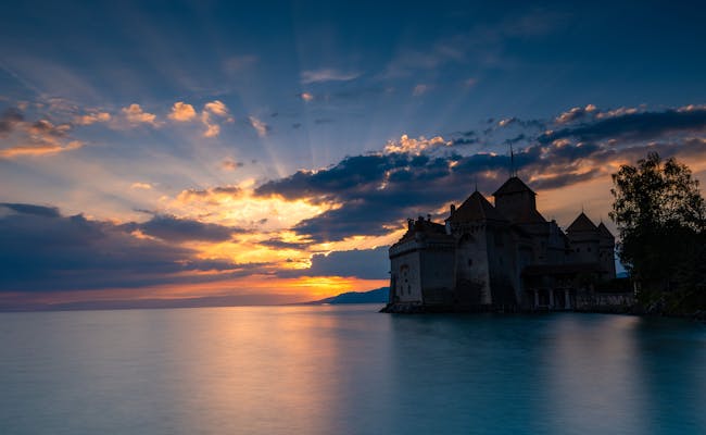 Schloss Chillon im Abendrot, ruhige Gewässer, Wolken mit Sonnenstrahlen