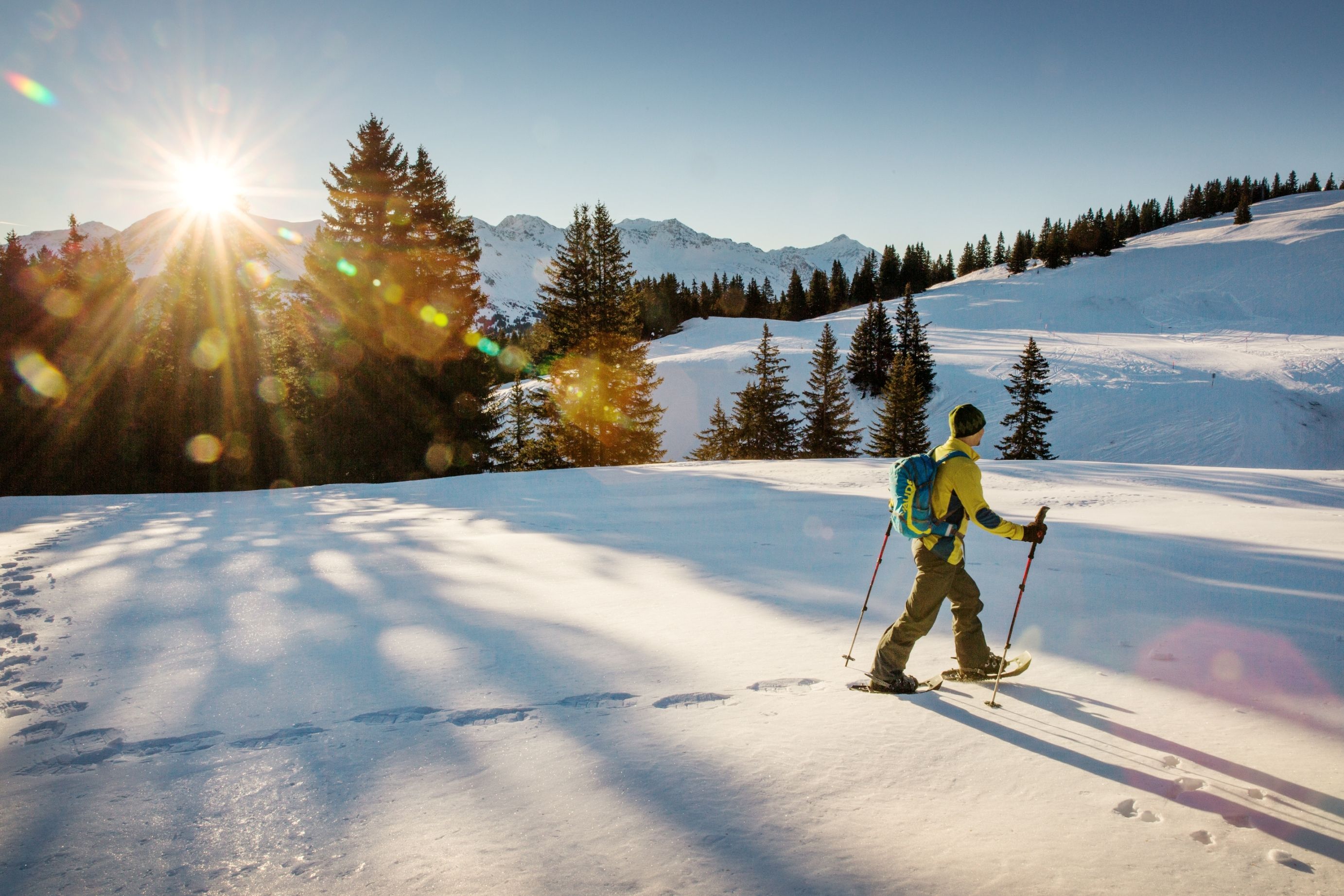 Randonnée en raquettes en Autriche au lever du soleil sur un terrain enneigé.