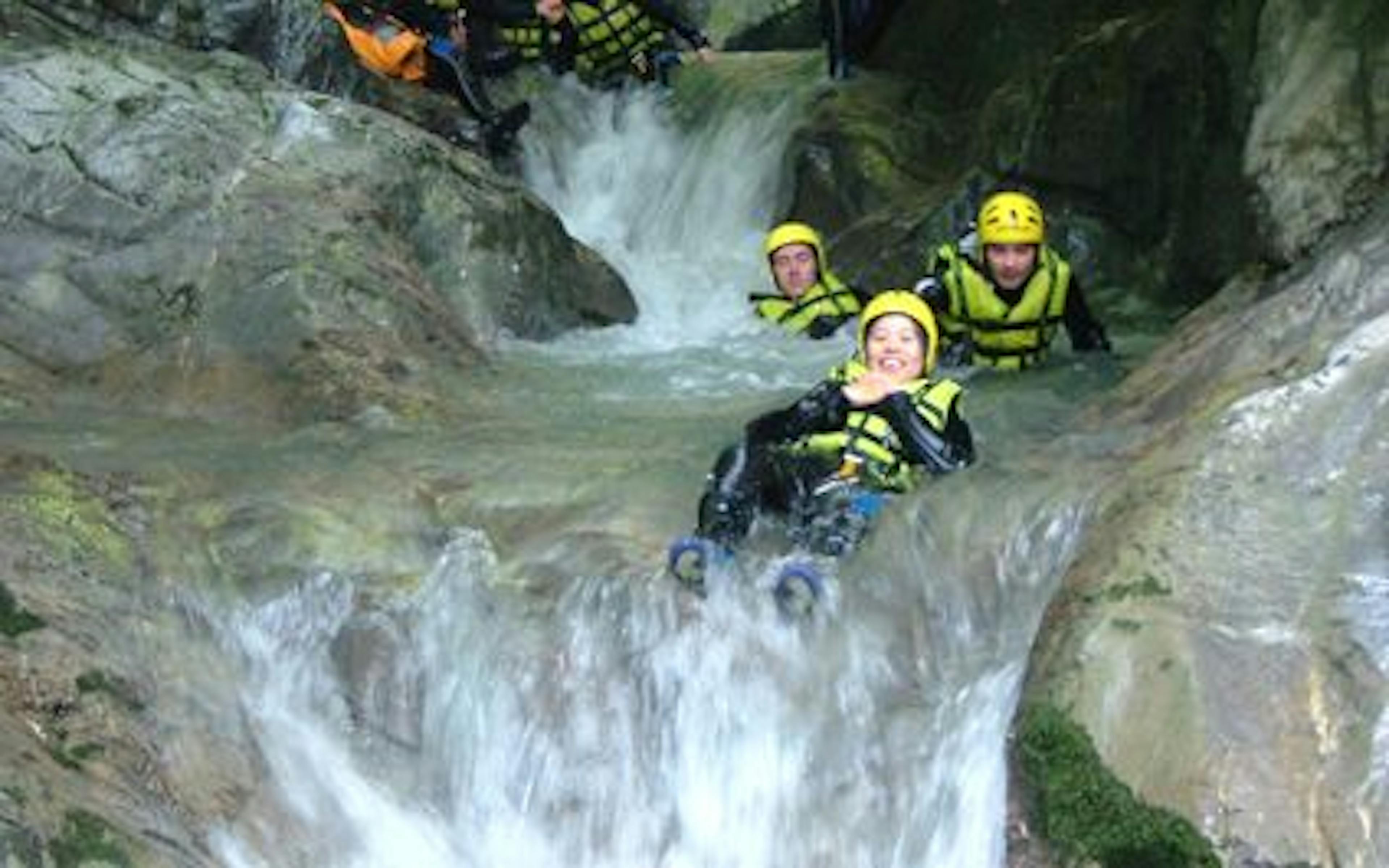 Canyoning Morge, Gruppe rutscht in Wasserfall, fließendes Wasser, Sommeraktivität.