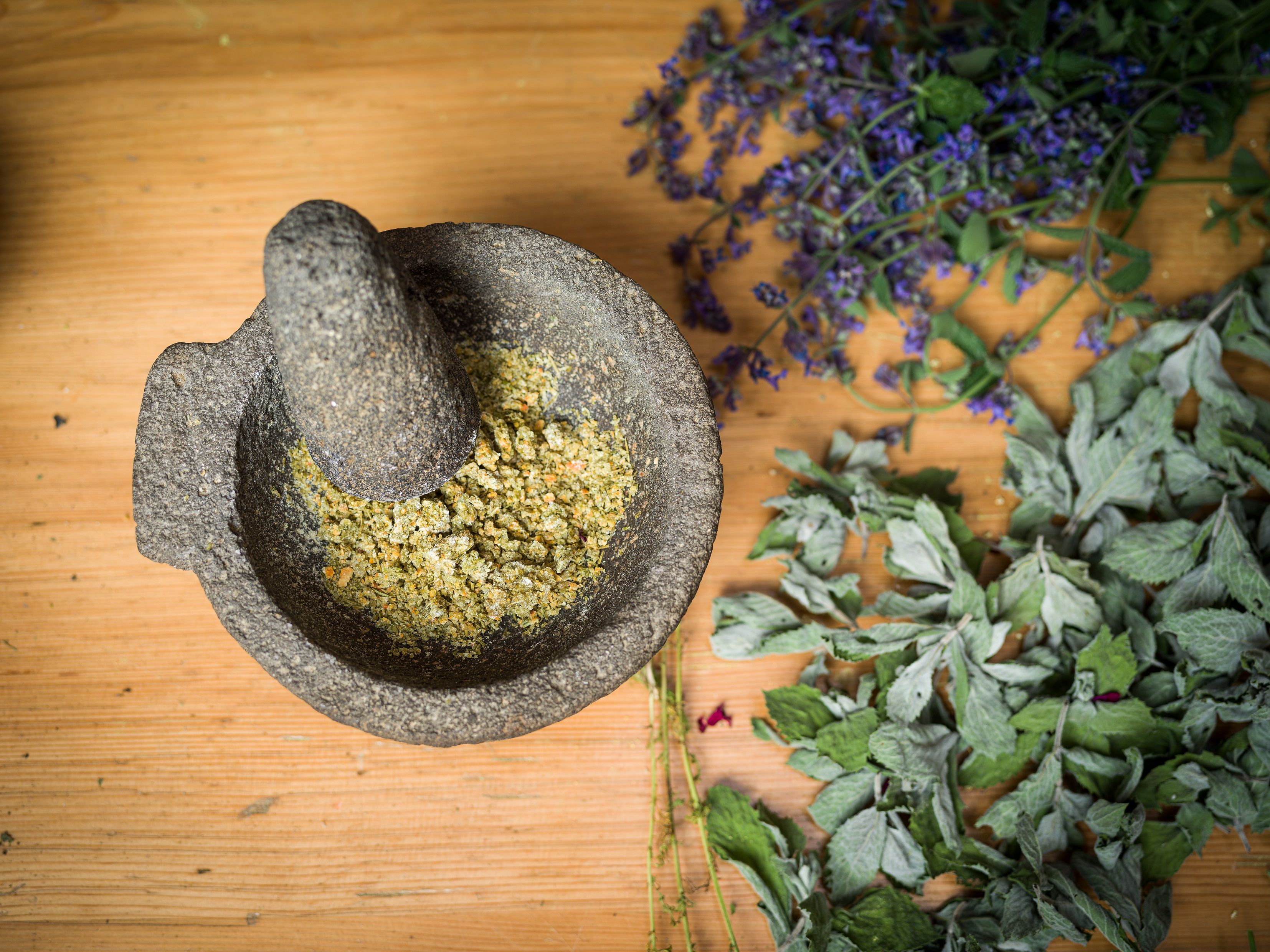 साहसिक जंगली जड़ी-बूटियों का मूसलीर ताजा जड़ी-बूटियों के साथ, प्राकृतिक उपचार और रसोई कला के लिए आदर्श।