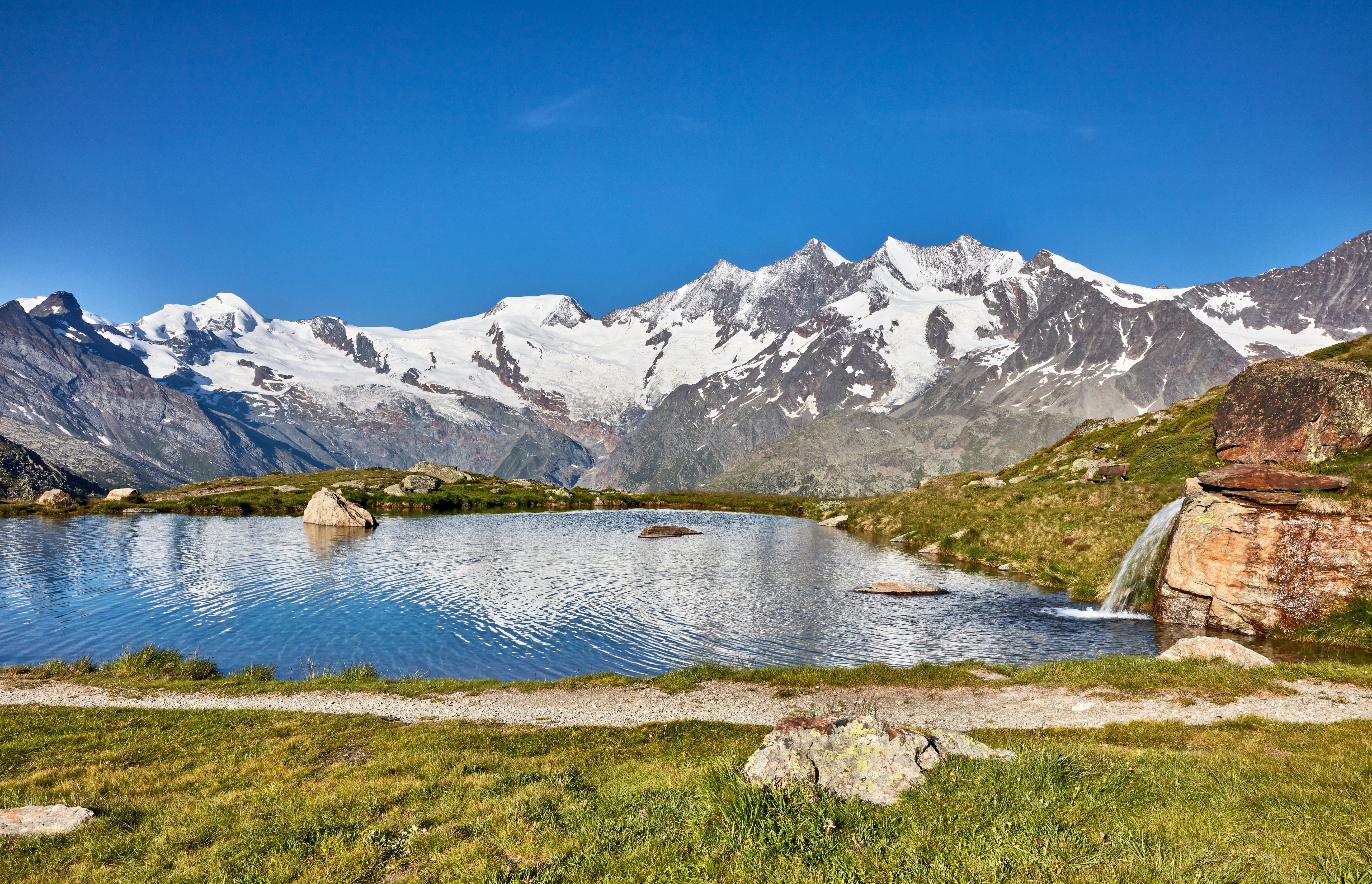 Кройцбодензе наас-Груд с заснеженными Альпами на фоне