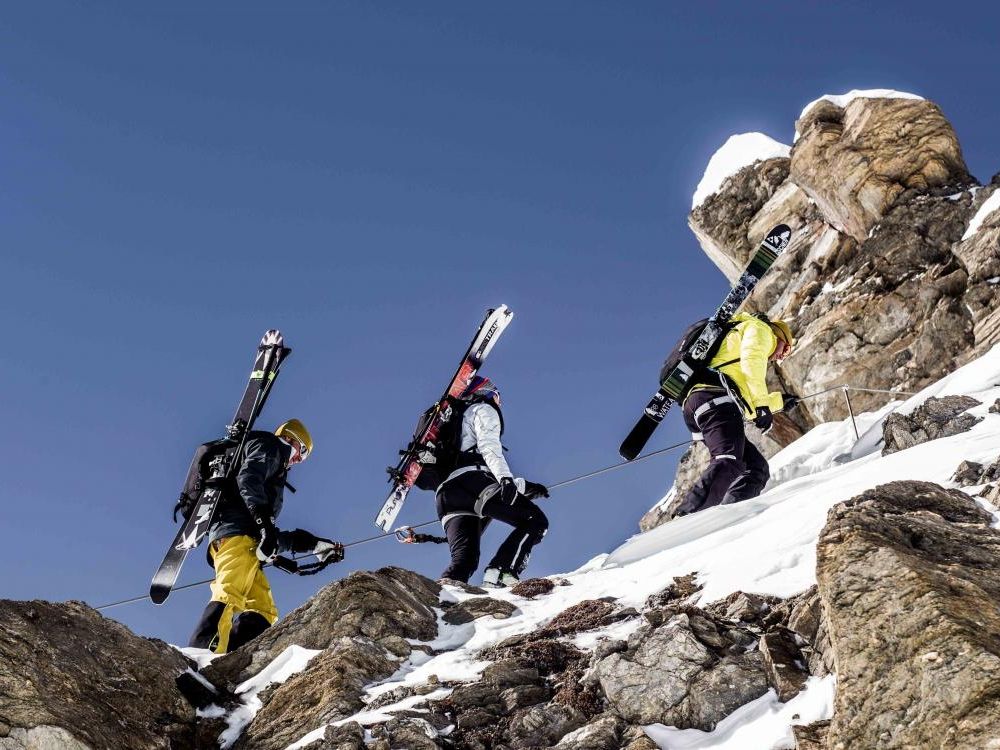 Ski tour La Traversata Zermatt with skiers during ascent, snow-covered rocks.