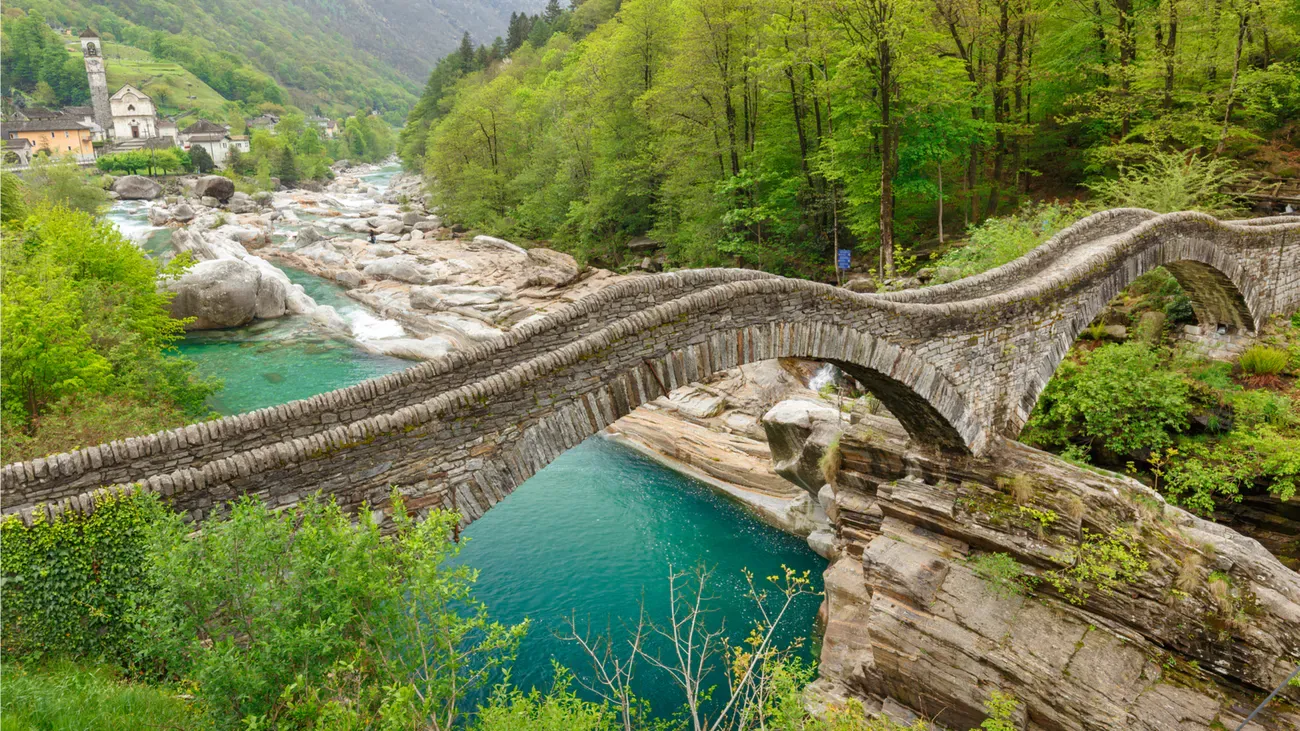 Ponte di Lavertezzo sul fiume Verzasca, circondata da foreste verdi e paesaggi rocciosi
