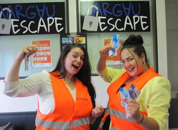 Deux femmes en gilets orange montrent des succès dans la salle d'évasion