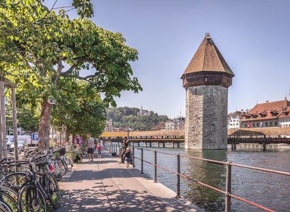 Kapellbrücke in Luzern met uitzicht op de watertoren en wandelaars aan de oever.