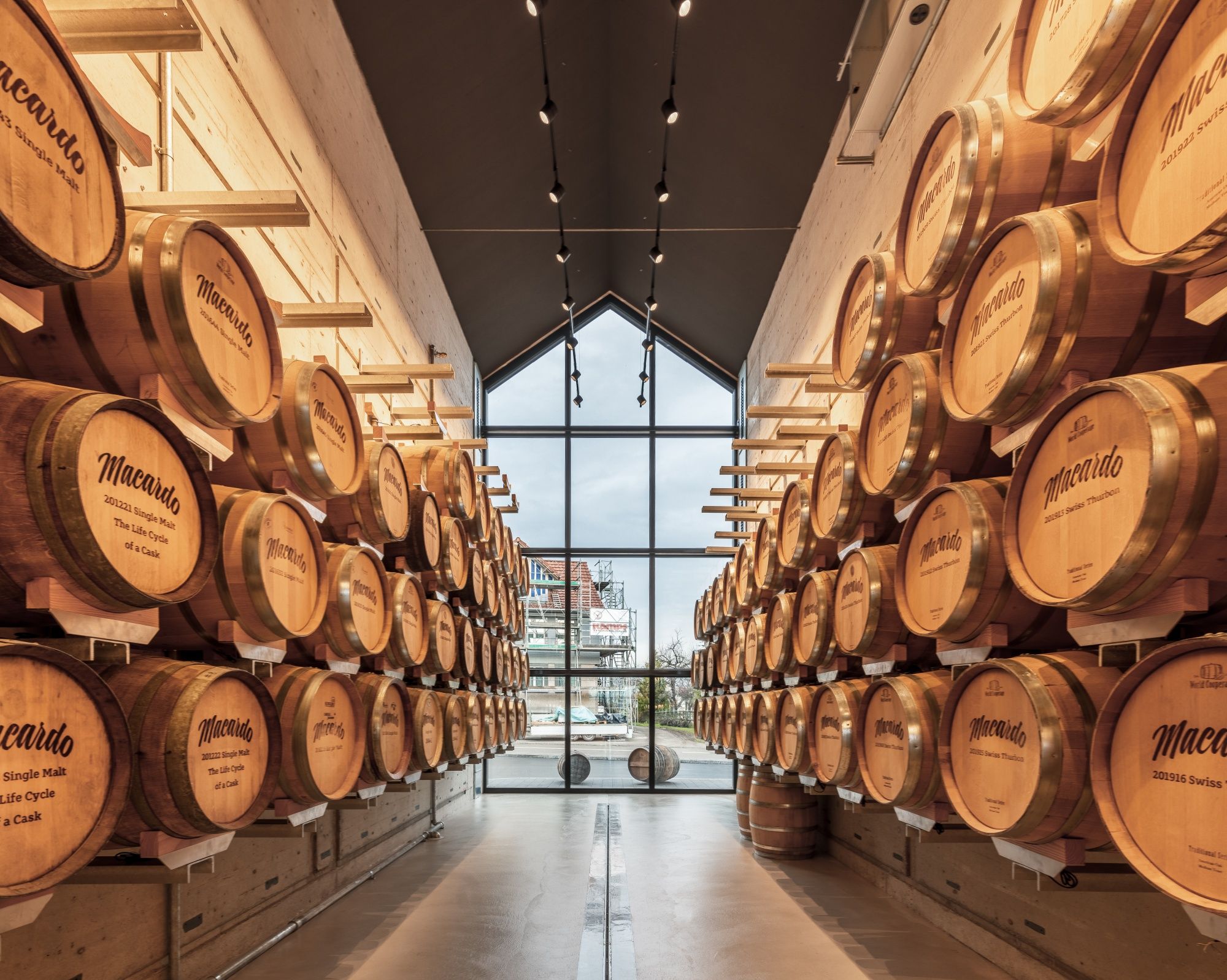 Macardo: Dřevěné sudy v moderním skladovacím areálu na whisky s výhledem na přístav, stylové a vřelé prostředí.