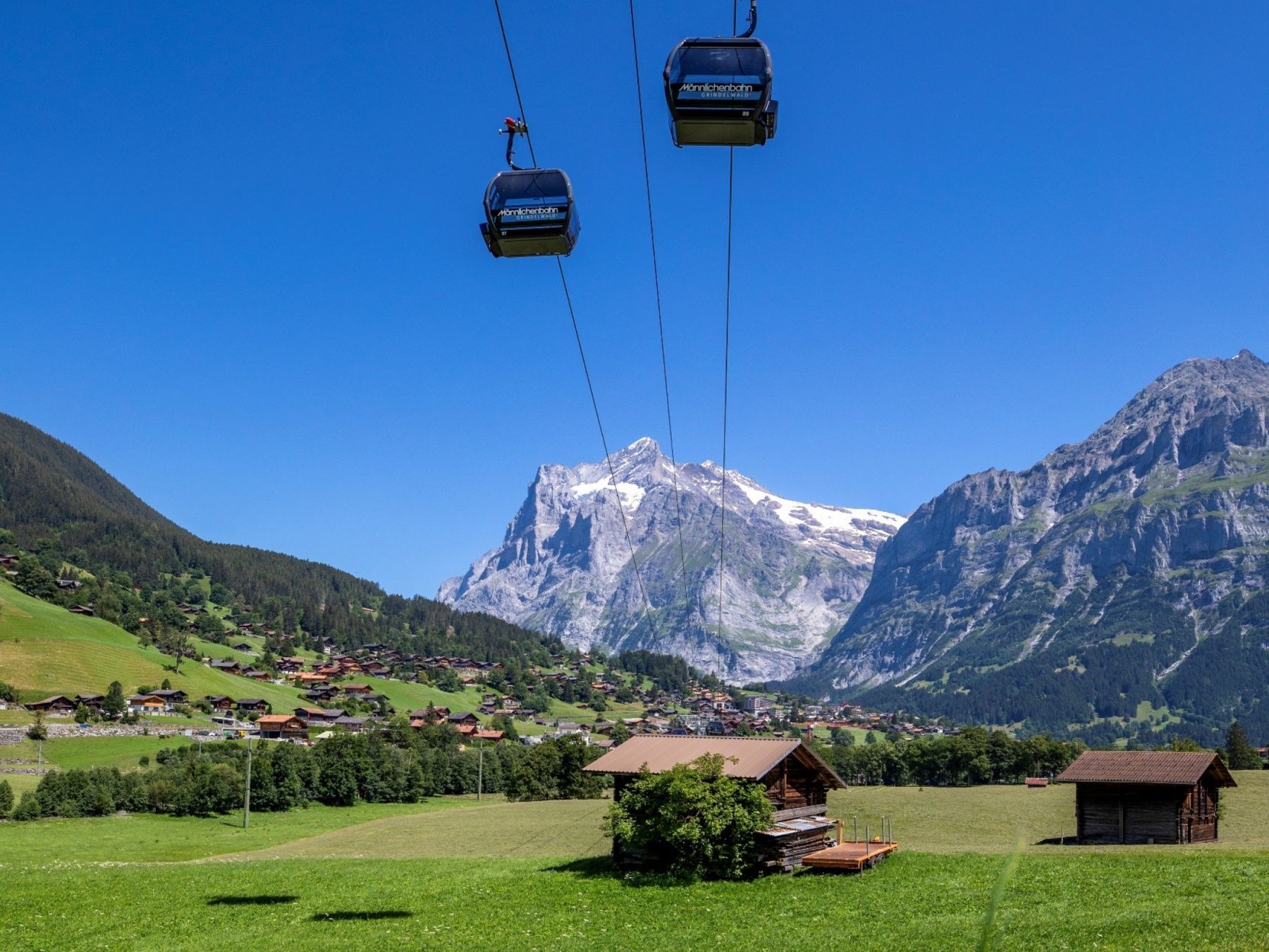 Jernbane Maennlichen med udsigt over Alperne, grønne enge og hytter i Wengen.
