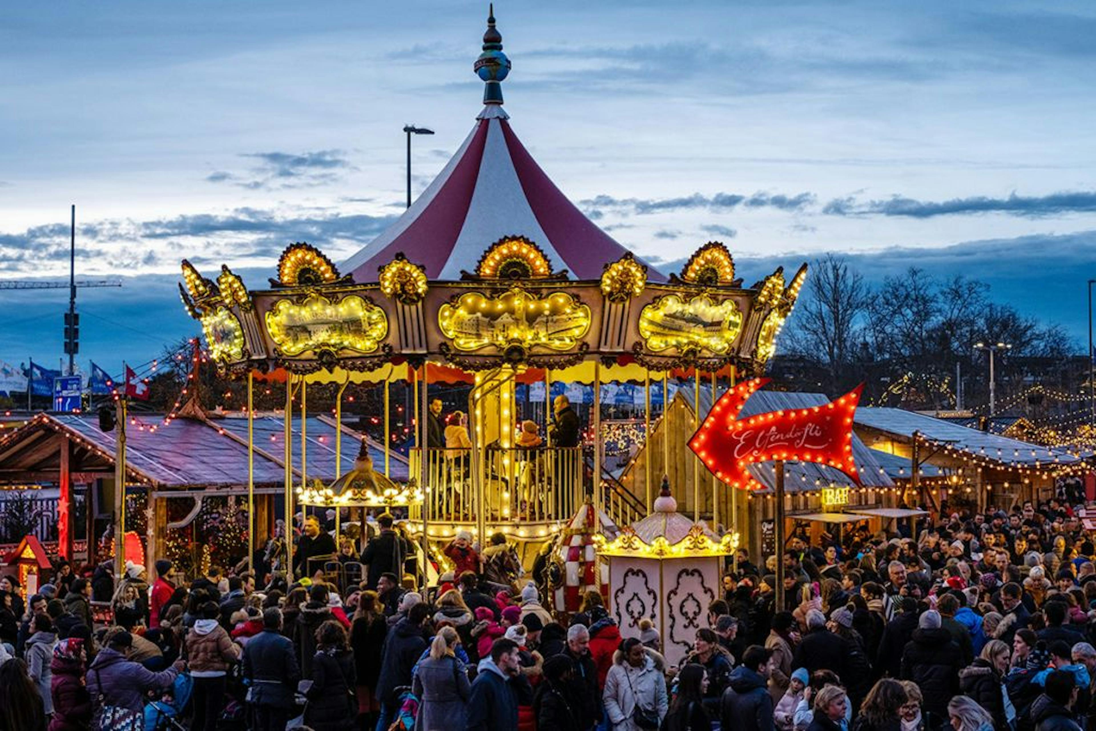 Kerstmarkt draaimolen met bezoekers bij schemering