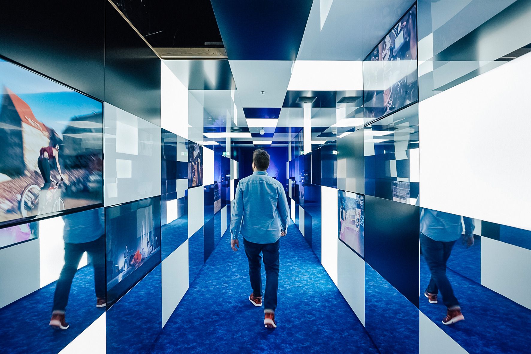 Οι επισκέπτες στο Ίδρυμα Μεταφορών της Ελβετίας περπατούν στην μοντέρνα αίθουσα έκθεσης με διαδραστικές οθόνες.