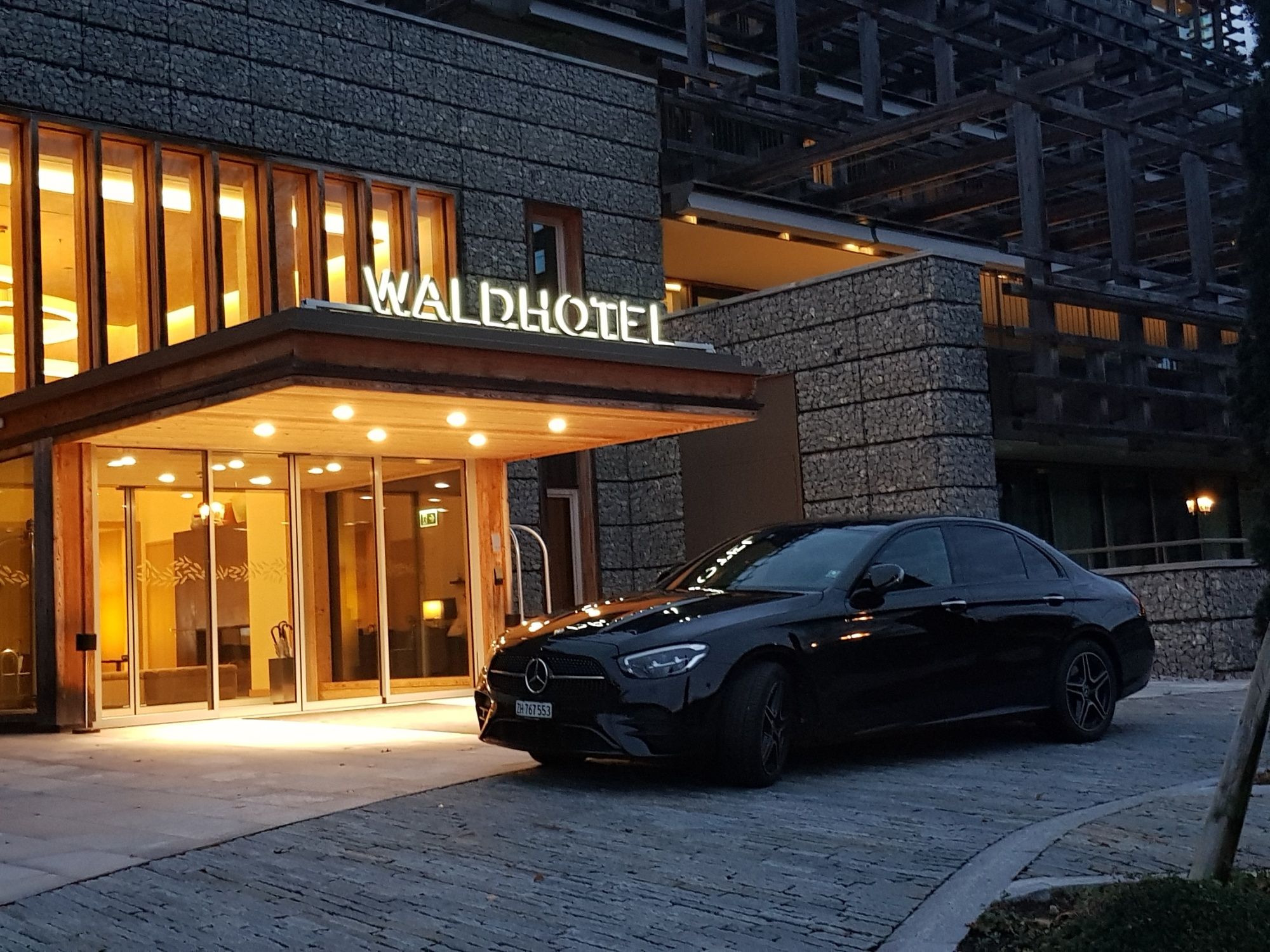 مرسيدس E-Class أمام فندق الغابة في بيئة جميلة - سيارة أنيقة وهندسة معمارية رائعة.