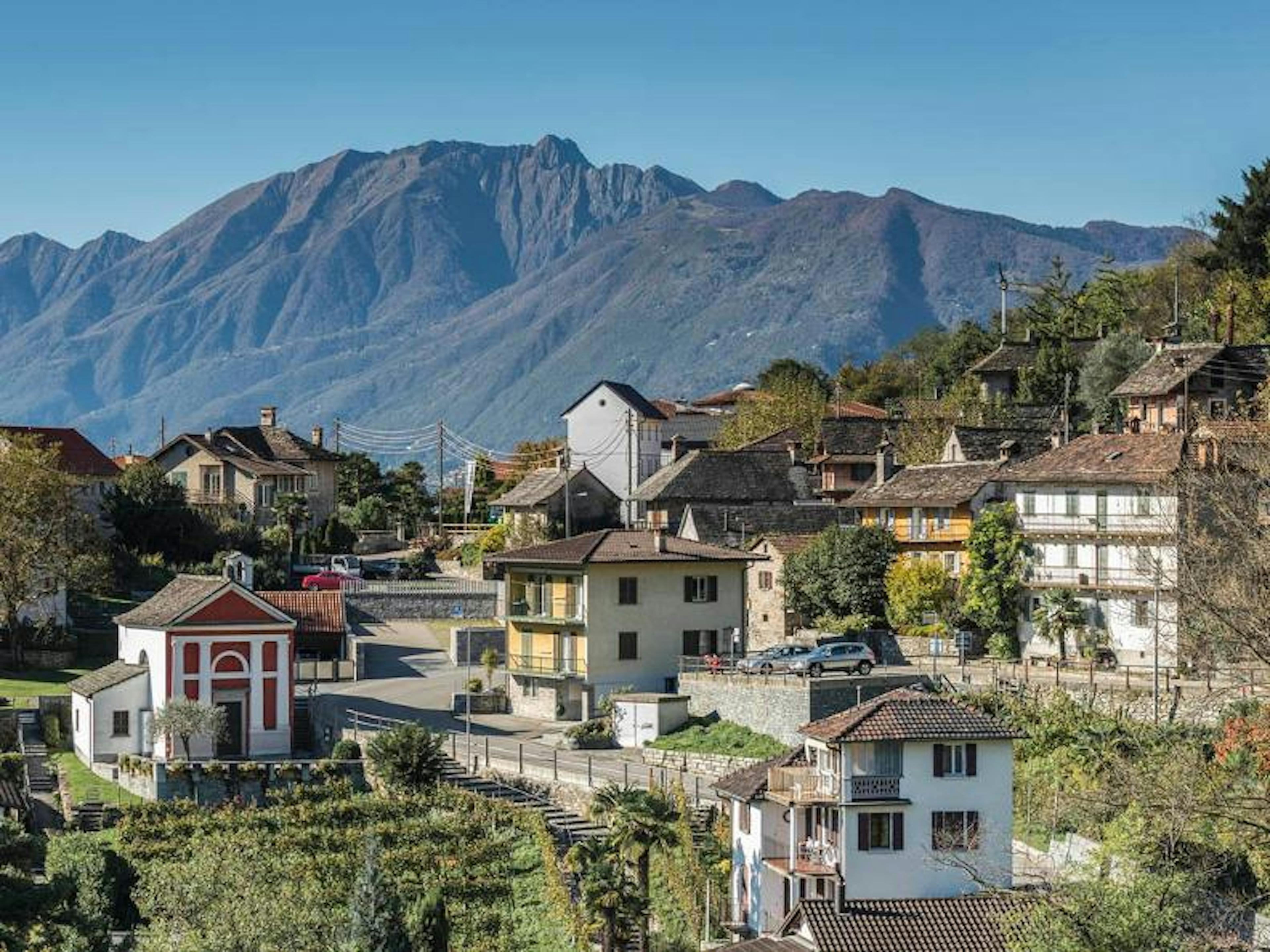 Vue sur Minusio avec des maisons traditionnelles et des montagnes.