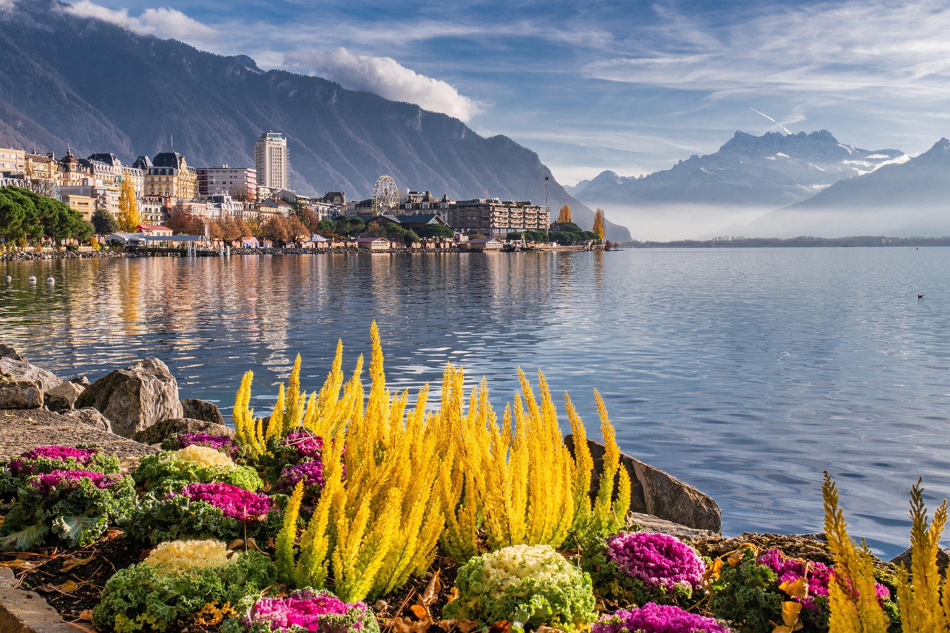 Montreux: ทิวทัศน์ที่สวยงามริมทะเลสาบเจนีวา พร้อมดอกไม้หลากสีและภูเขาอยู่เบื้องหลัง.