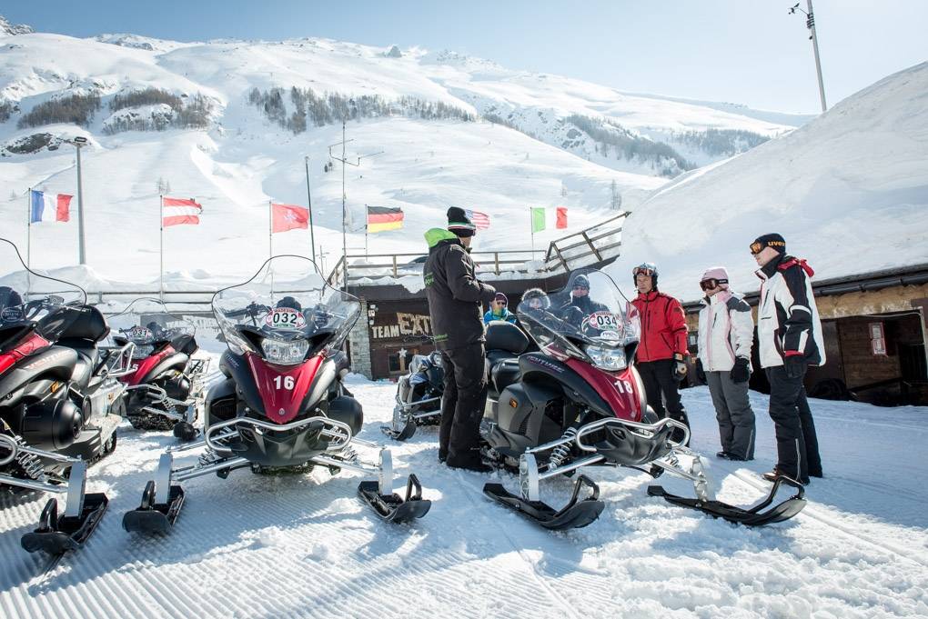 Tour de motoneige au col de Splügen avec des touristes et des véhicules.