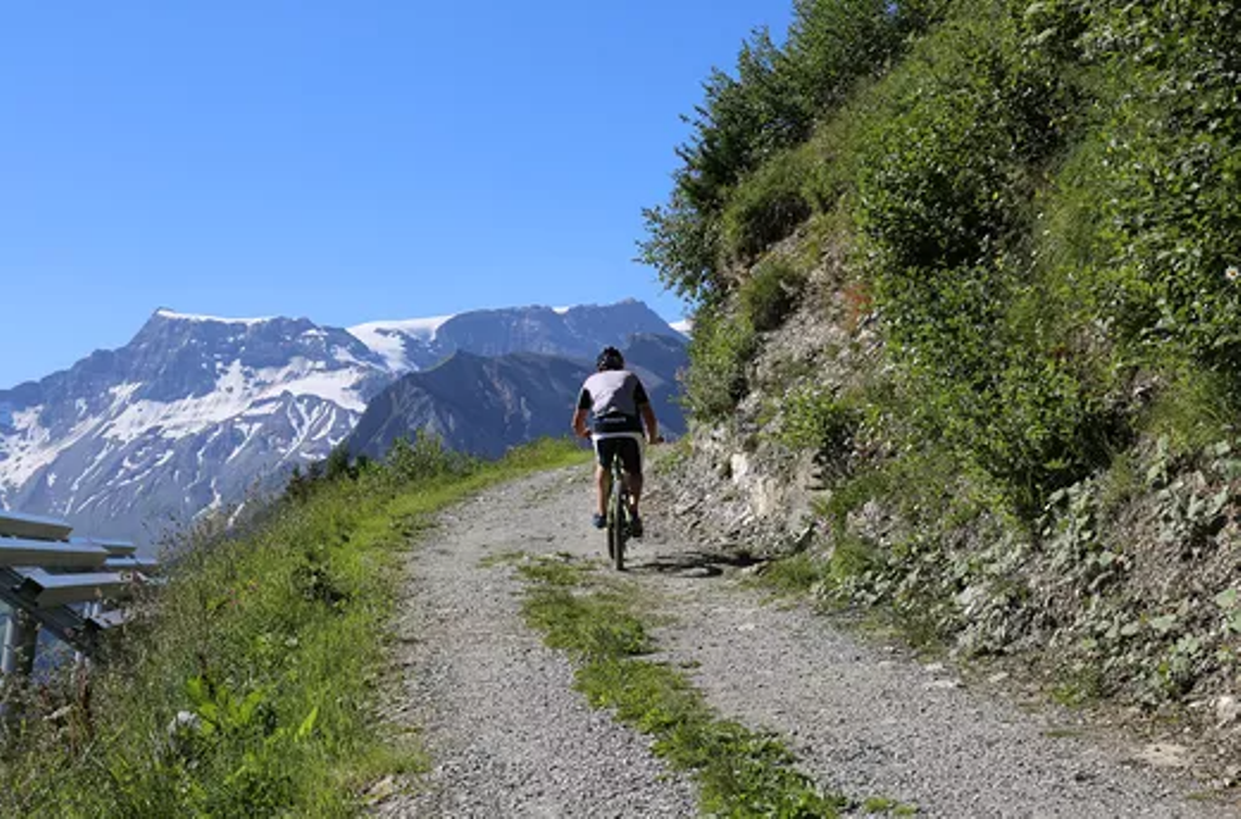Mountainbiker su un sentiero ghiaioso alla Tschentenalp, circondato da montagne.