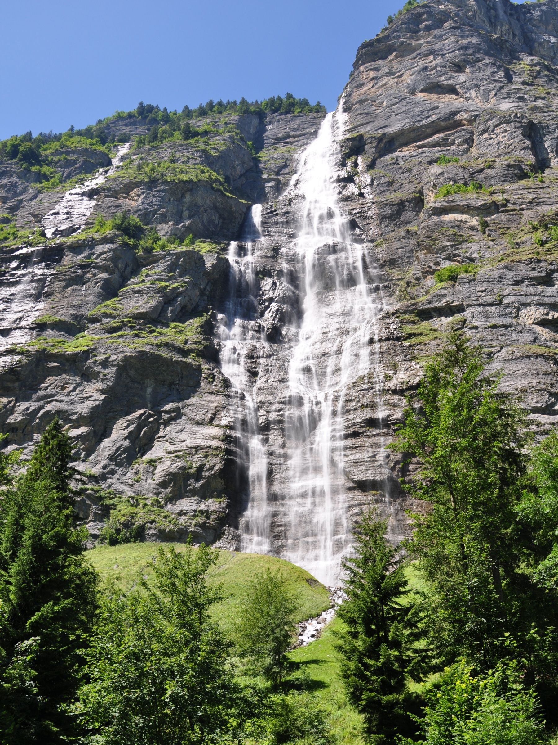 น้ำตก Muerrenbachไหลผ่านโขดหินในประเทศสวิตเซอร์แลนด์ล้อมรอบด้วยต้นไม้