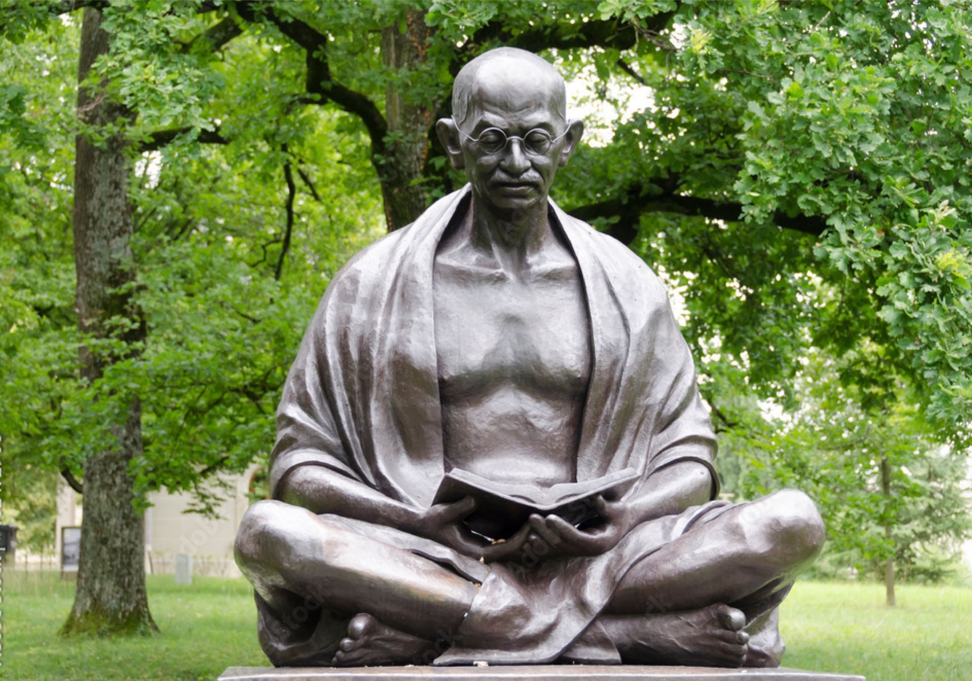 Άγαλμα του Μοχάμεντα Γκάντι στη Γενεύη, ένα πολιτιστικό αξιοθέατο σε εξωτερικό χώρο ανάμεσα σε δέντρα.