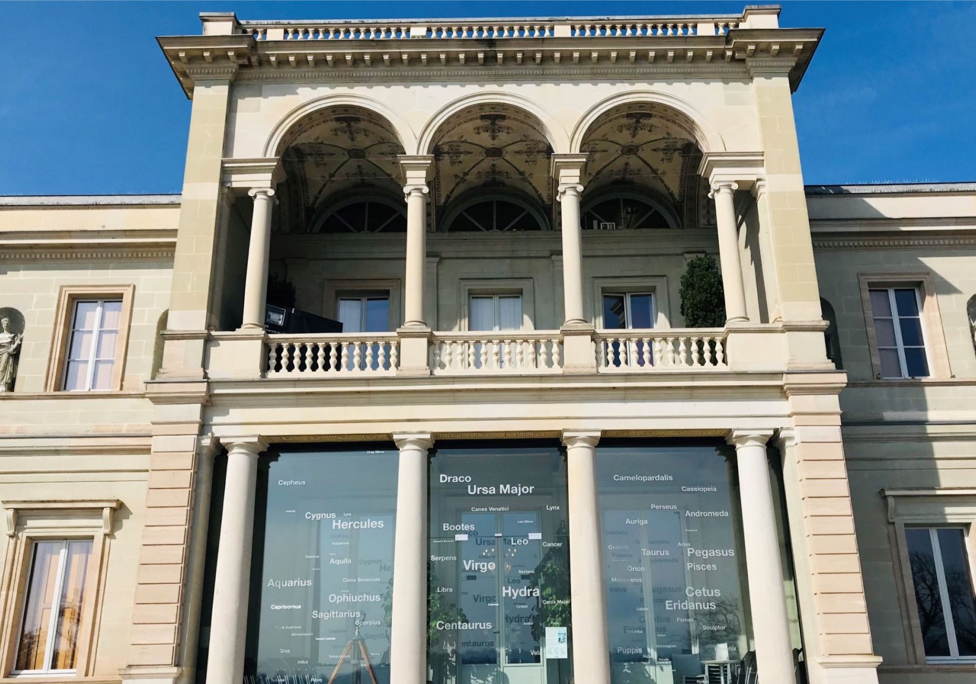 Explorial Γενεύη: εντυπωσιακό ιστορικό κτίριο με έργο τέχνης μπροστά σε μια γραφική ατμόσφαιρα.