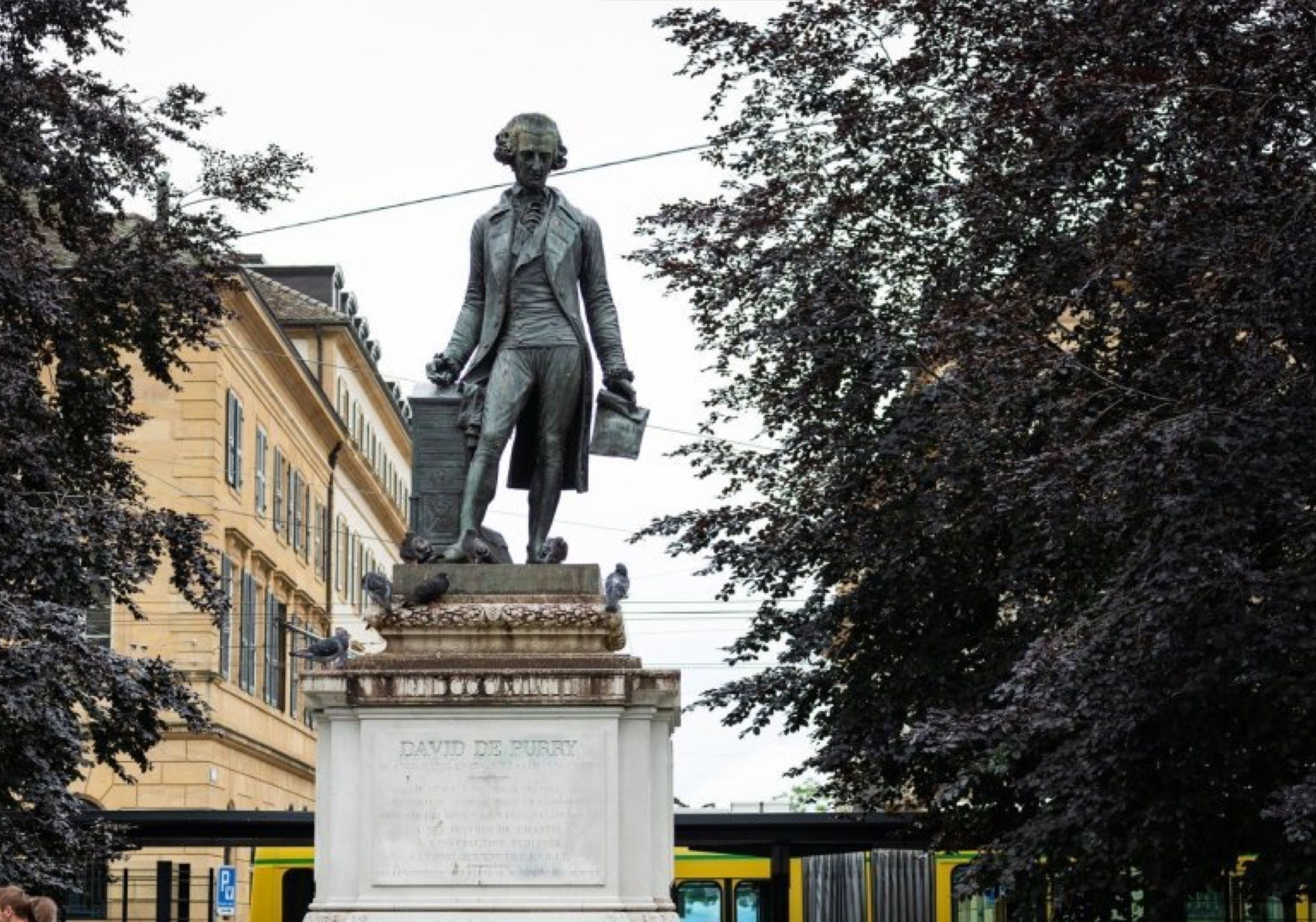 诺沙泰尔：位于市中心的戴维·德·普里雕像，周围环绕着树木和建筑。