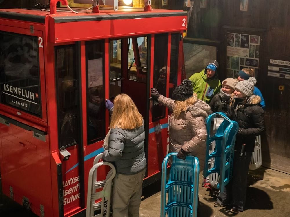 Tobogán nocturno en Suiza con amigos en invierno. Diversión en trineo para grupos en un paisaje montañoso.