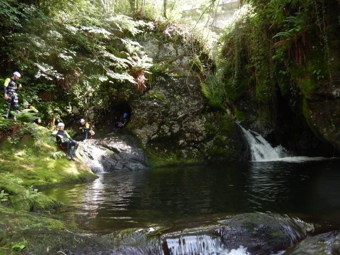 滝を背景にしたヴィラでのキャニオニング体験コースの参加者たちによる自然のプール。