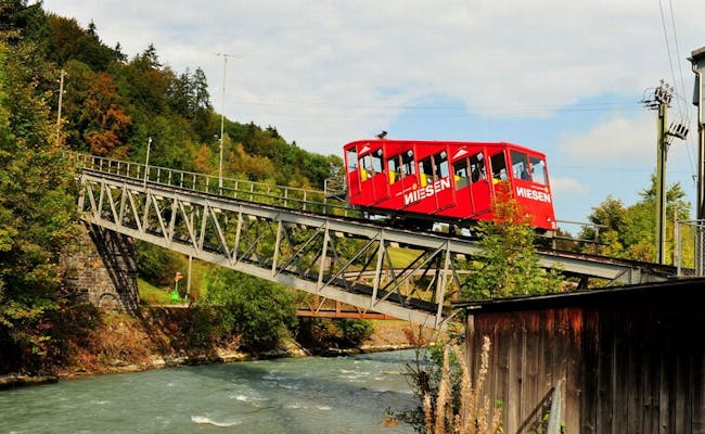 La Niesenbahn atraviesa un puente en Niesen, rodeado de árboles y un río