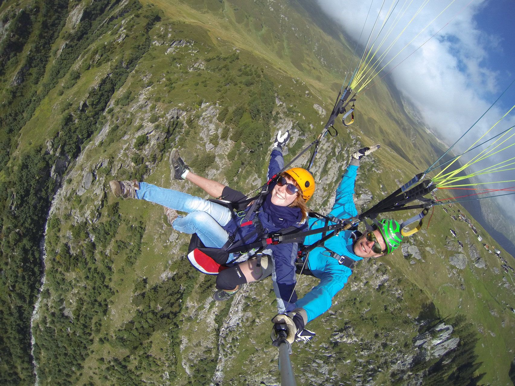 باراگلایدینگ بلیپ مع شخصين في الهواء فوق المناظر الطبيعية