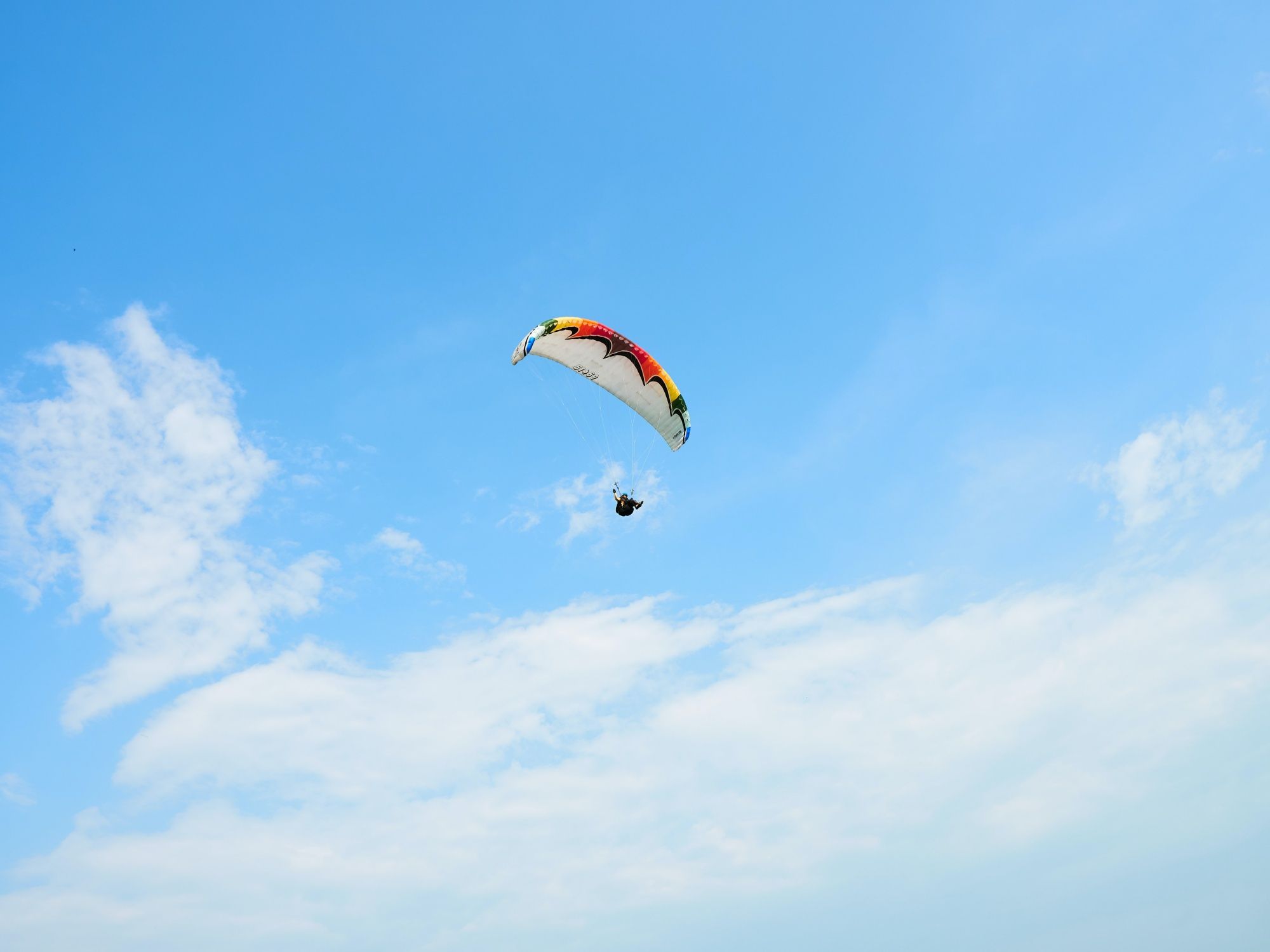Paralayang di bawah langit biru, awan lembut, 2023