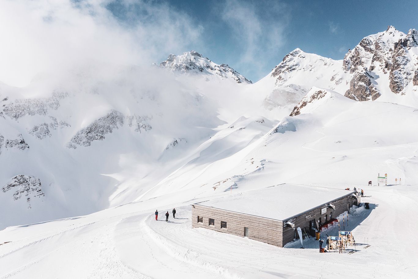 ピゾルヒュッテ：雪に覆われた山とスキーヤーのいる冬の居心地の良い山小屋。