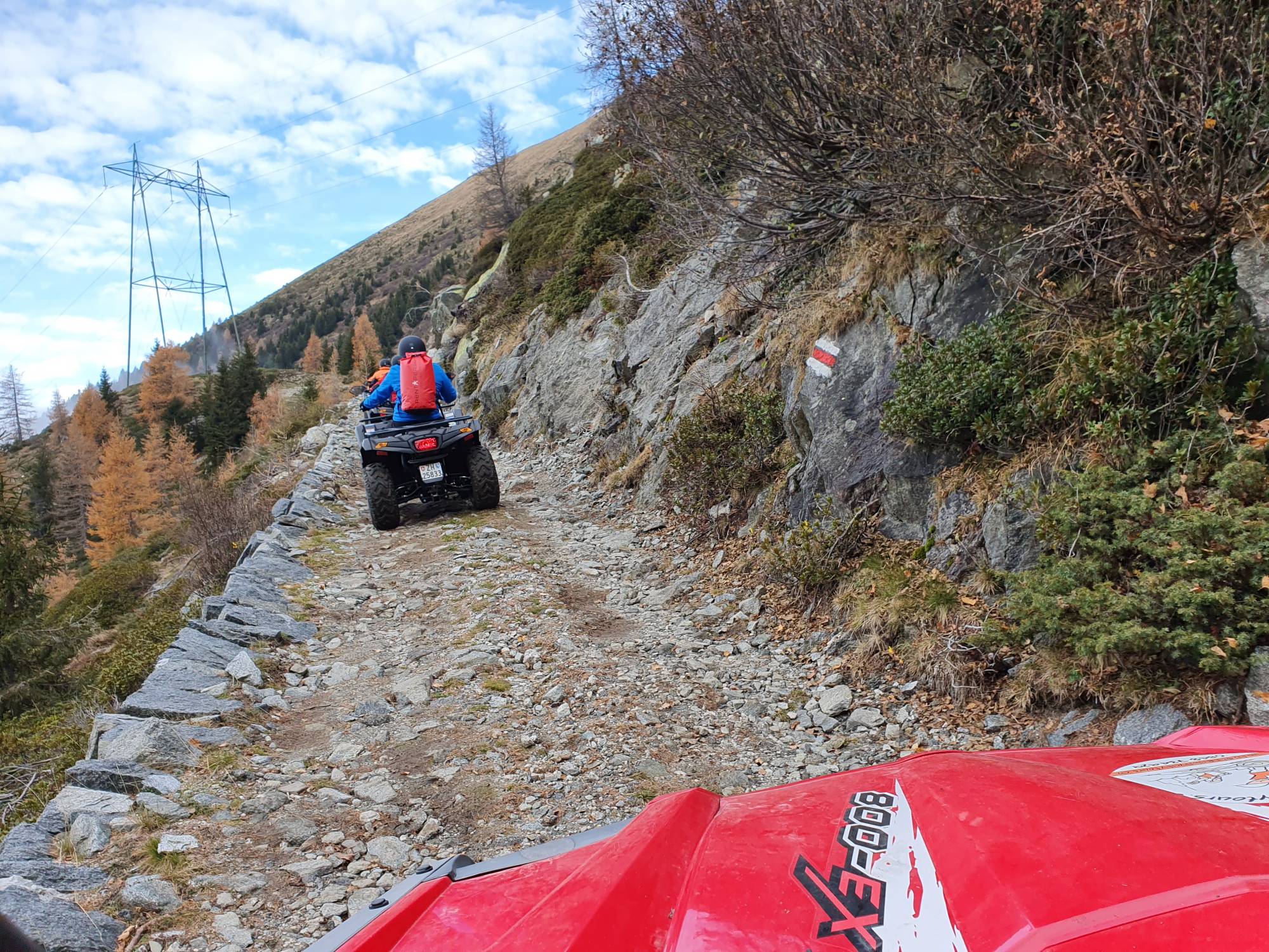 Tour en quad por el paso Splügen con ATV en camino de grava en las montañas. Colores de otoño visibles.