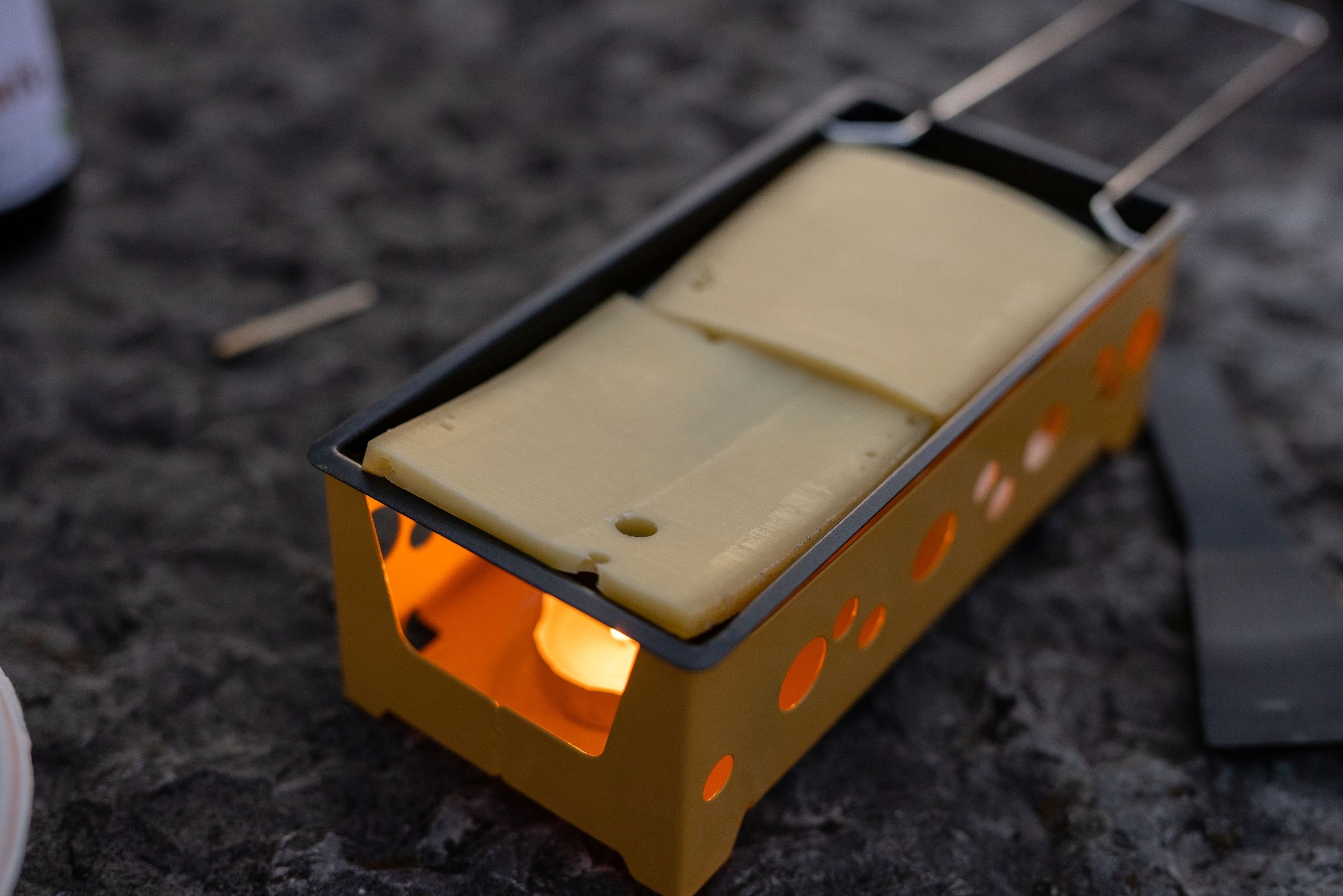 Raclette: Keju cair yang meleleh di atas alat pembakar semasa berkhemah, sesuai untuk malam musim sejuk di luar rumah.