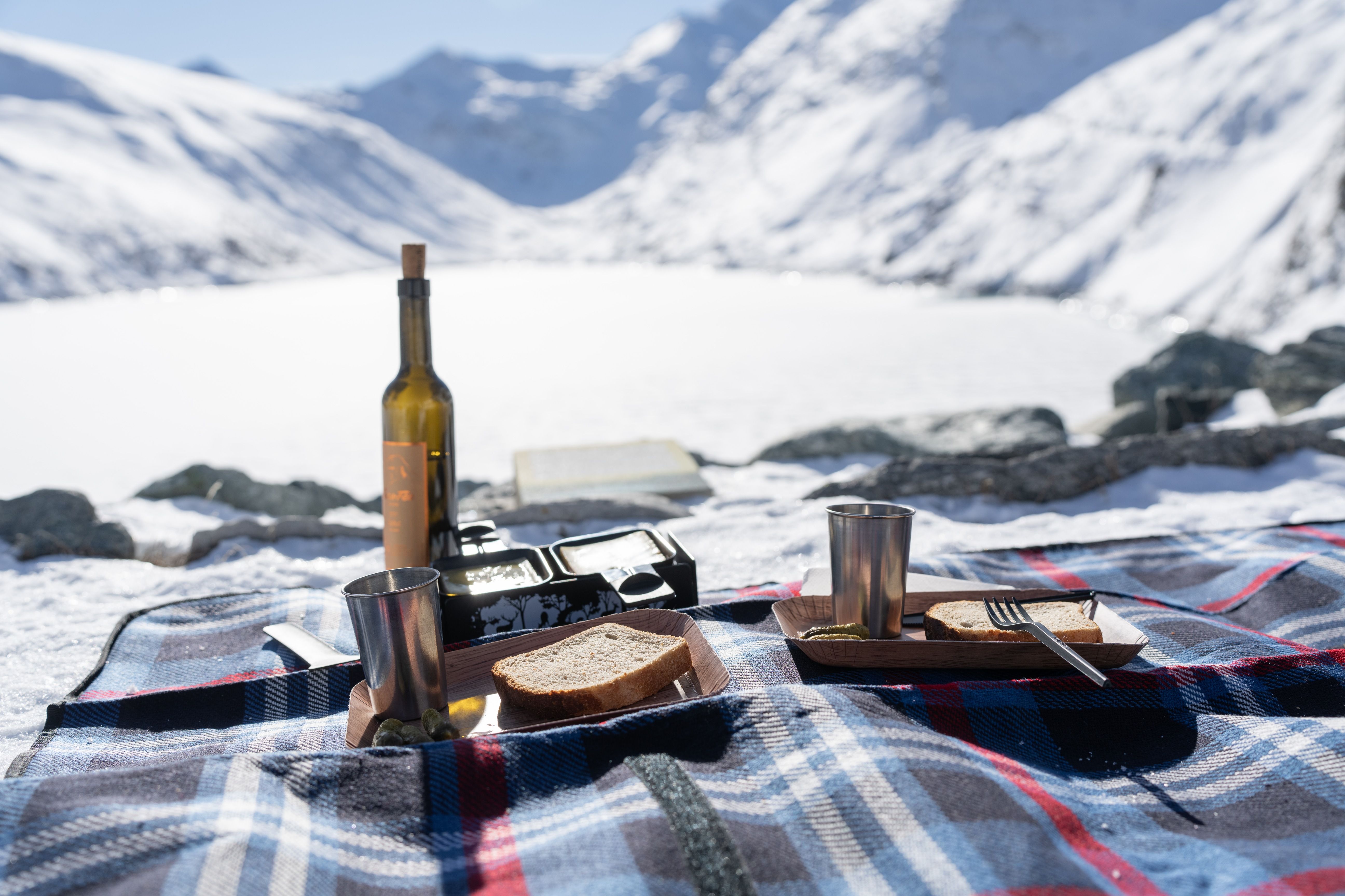 Raclette na natureza com vista para a paisagem montanhosa invernal no Saastal.