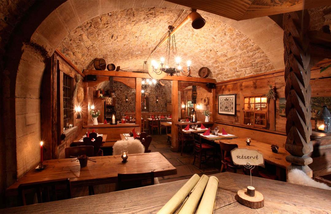 Ristorante al chiuso con legno rustico, tavoli e luce suggestiva