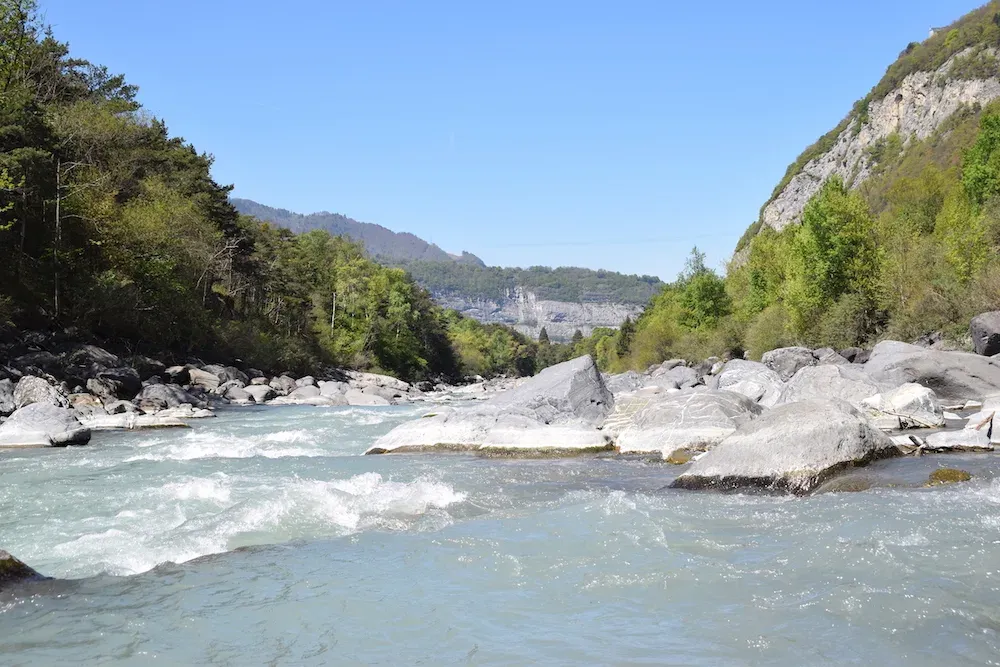 La rivière Rhône coule à travers un paysage verdoyant avec des rochers. Air clair et ciel bleu.