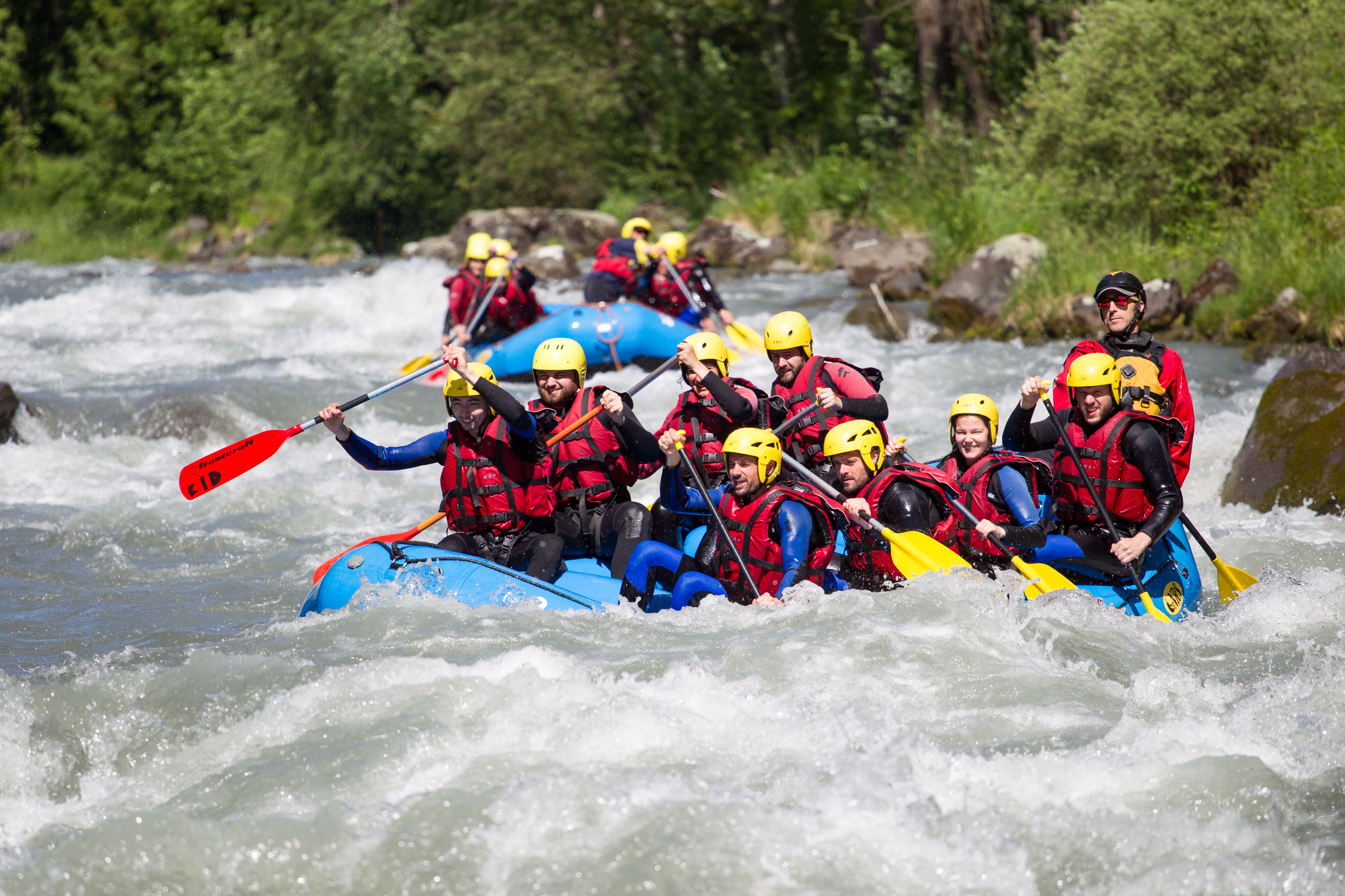 Avventura di rafting su acque selvagge con un gruppo in elmetti gialli e giubbotti rossi