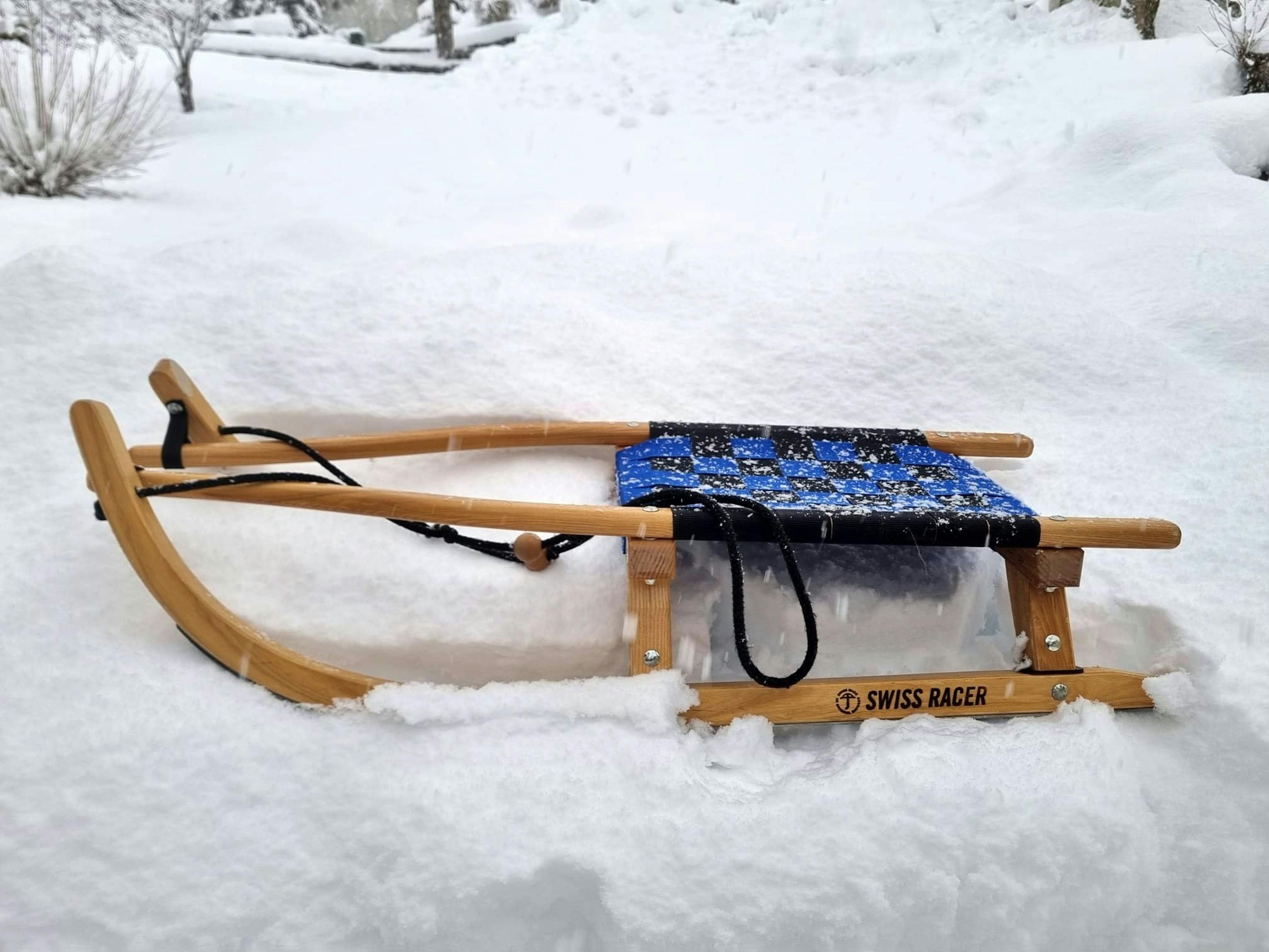 Rodelschlitten Grindelwald liegt in frischem Schnee, umgeben von winterlicher Landschaft.