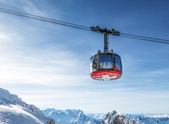 Kolej linowa Rotair na Titlis z zaśnieżonymi górami pod niebieskim niebem.
