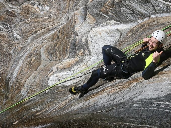 Deslizamiento Canyoning Pro Val Grande con participante en traje de neopreno, equipo de escalada y cuerda