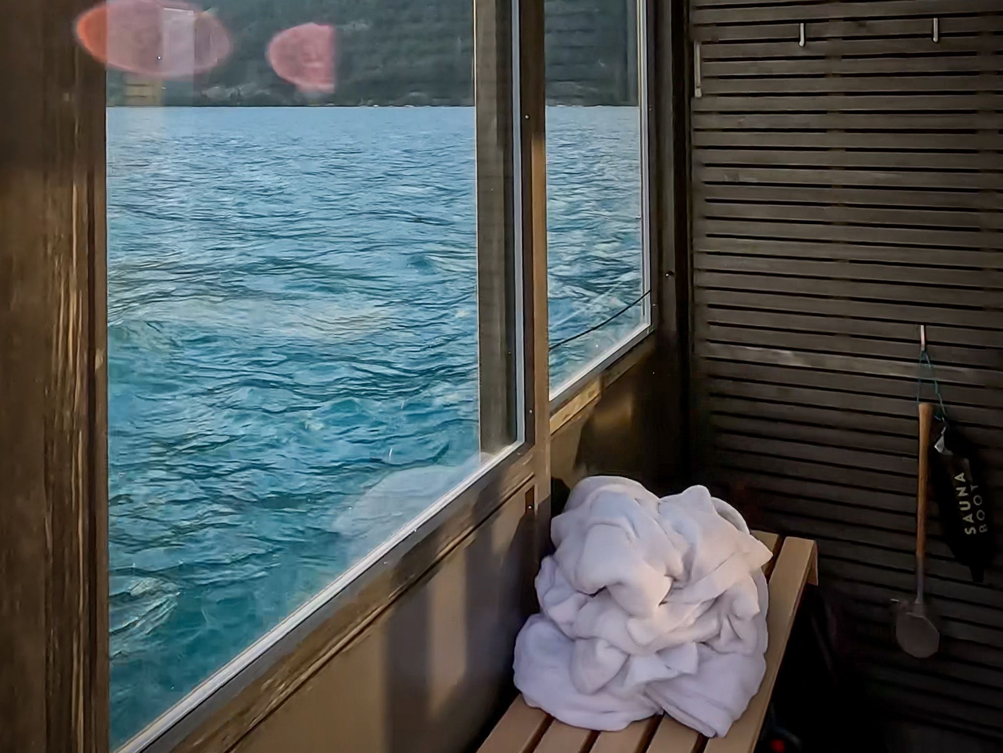 Barcă de sauna cu vedere la lac, ideală pentru relaxare și wellness în natură.