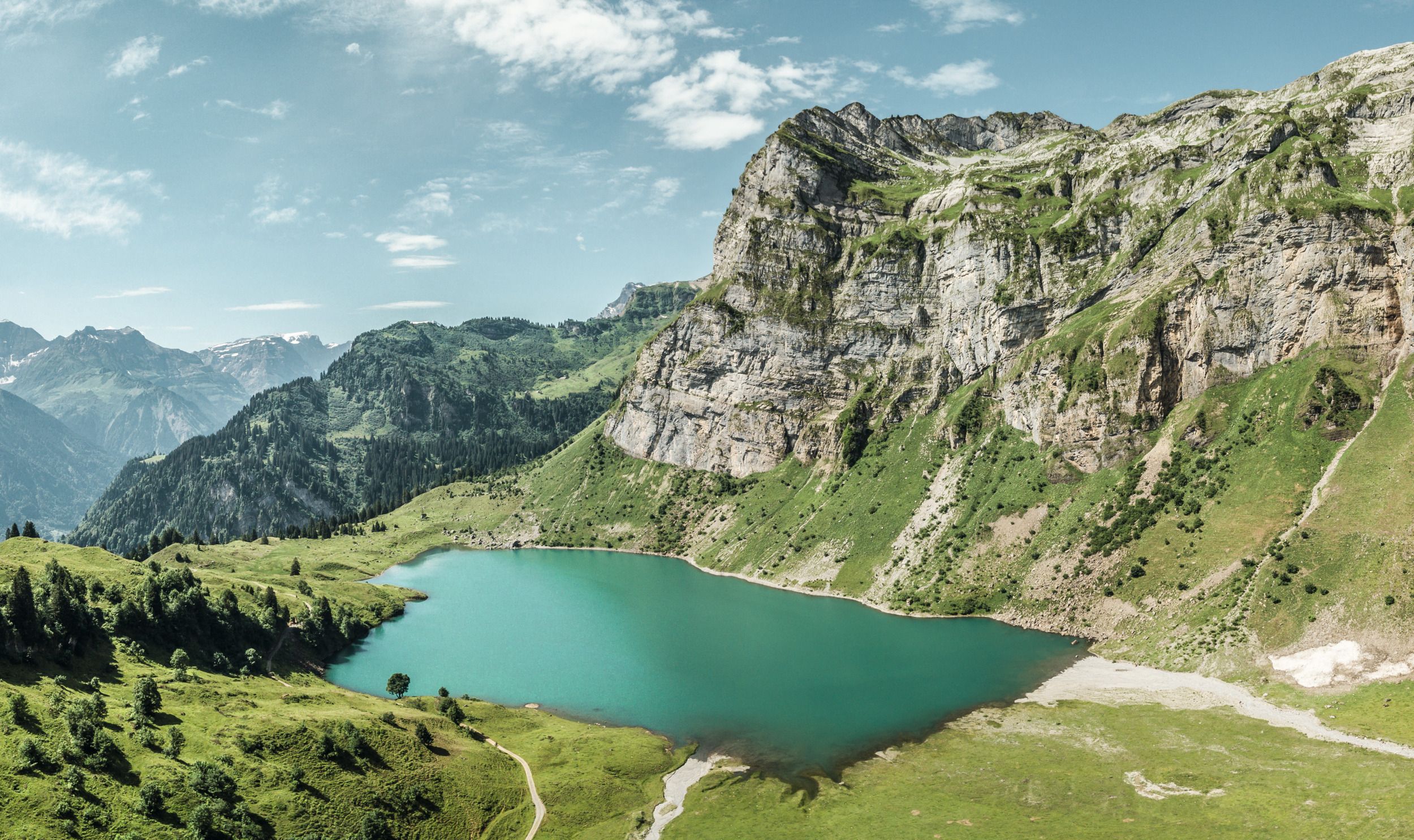 Oberblegisee Braunwald: malerisk bjerglandskab med grønt vand og omkringliggende Alper, perfekt for naturelskere.