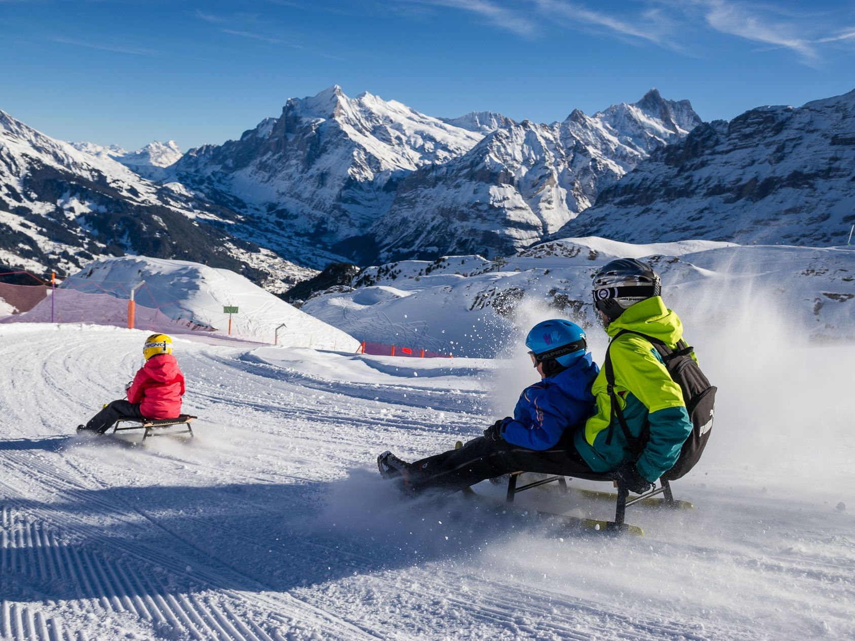 Аренда саней в Гриндельвальде, люди катаются на заснеженной трассе
