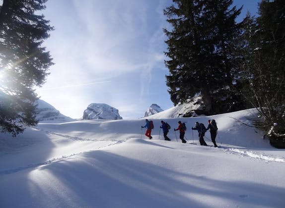 Tour di ciaspole nel val Frümsel: escursionisti nella neve davanti a un paesaggio invernale pittoresco.